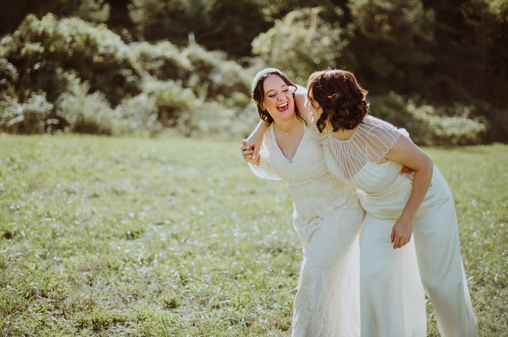 Las dos novias riendo abrazadas en el campo durante la sesión de pareja en This Must Be The Place