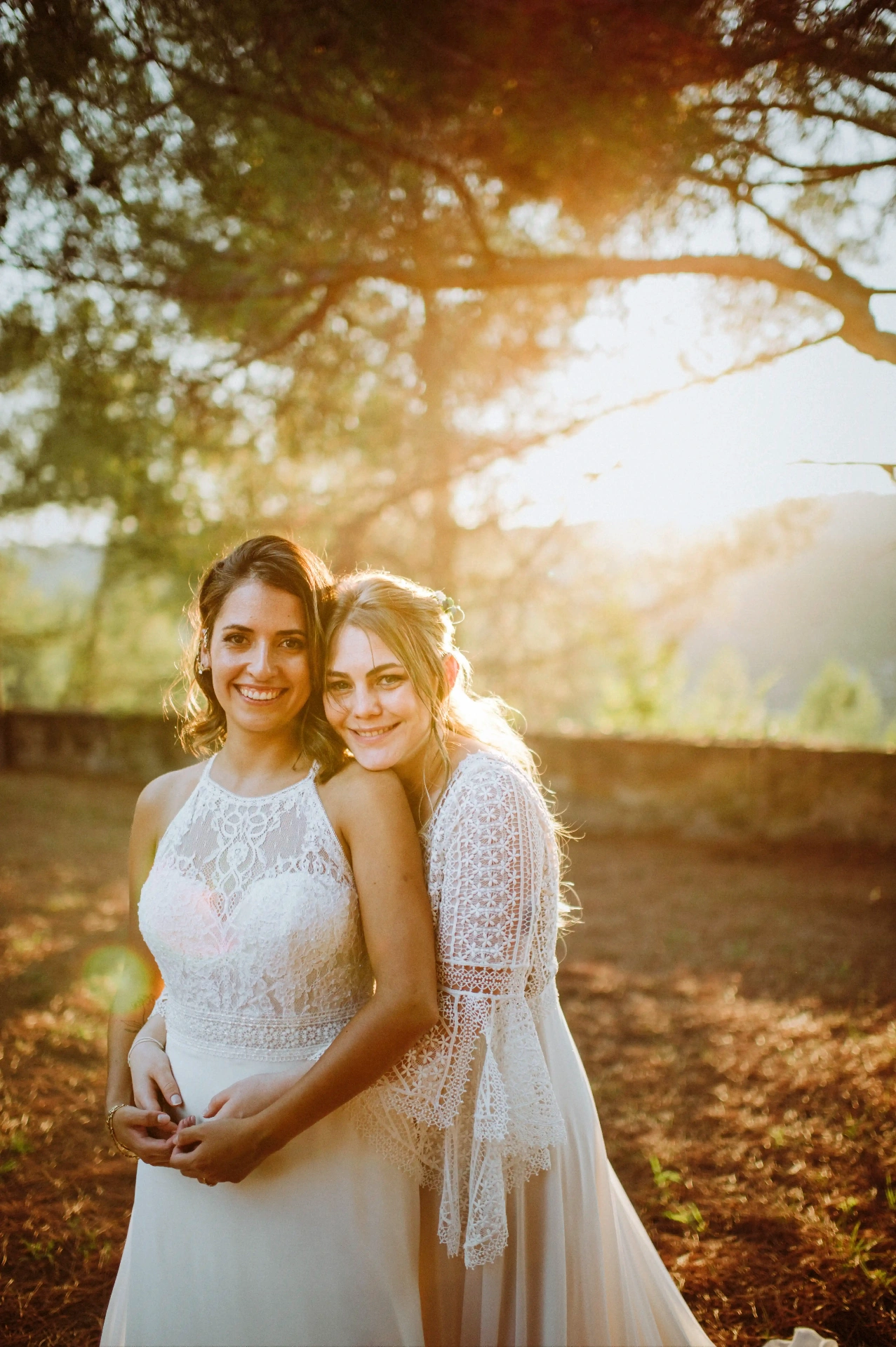 boda LGTBI en Ca n'Alzina (Rubió) — primer plano de las novias abrazadas mirando a cámara con luz cálida