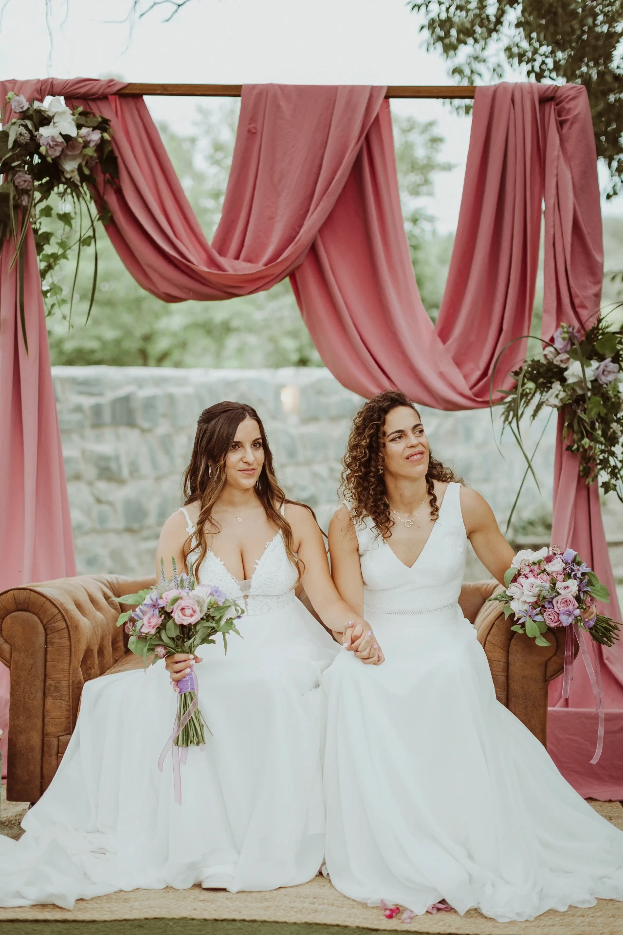 boda LGTBI en El Xaloc, Calders — las novias sentadas juntas en un sofá de cuero durante la ceremonia