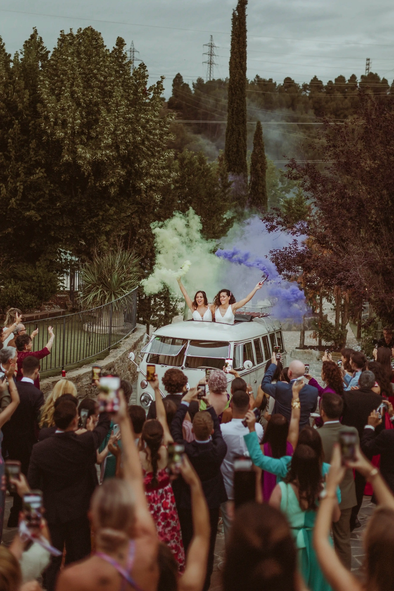 boda LGTBI en El Xaloc, Calders — despedida de las novias desde una furgoneta VW clásica con humos de colores y los invitados alrededor