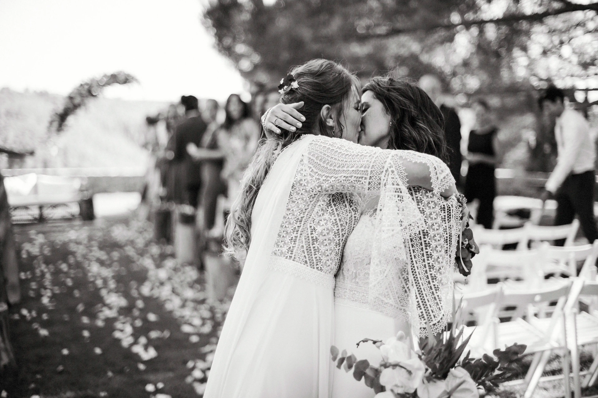 boda LGTBI en Ca n'Alzina — beso íntimo de las novias abrazadas al final del pasillo con pétalos en el suelo