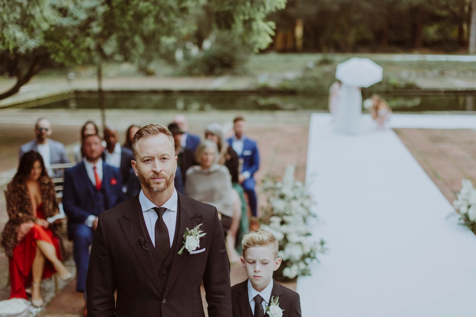 Lee y su hijo caminando hacia el altar en la ceremonia de boda en los jardines de Bell Recó Argentona