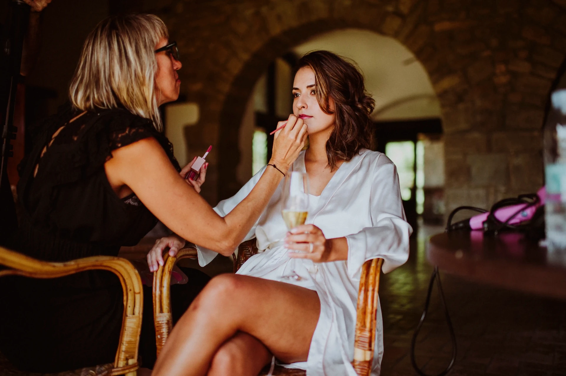 boda LGTBI en Ca n'Alzina — maquilladora perfilando los labios de la novia bajo los arcos de piedra