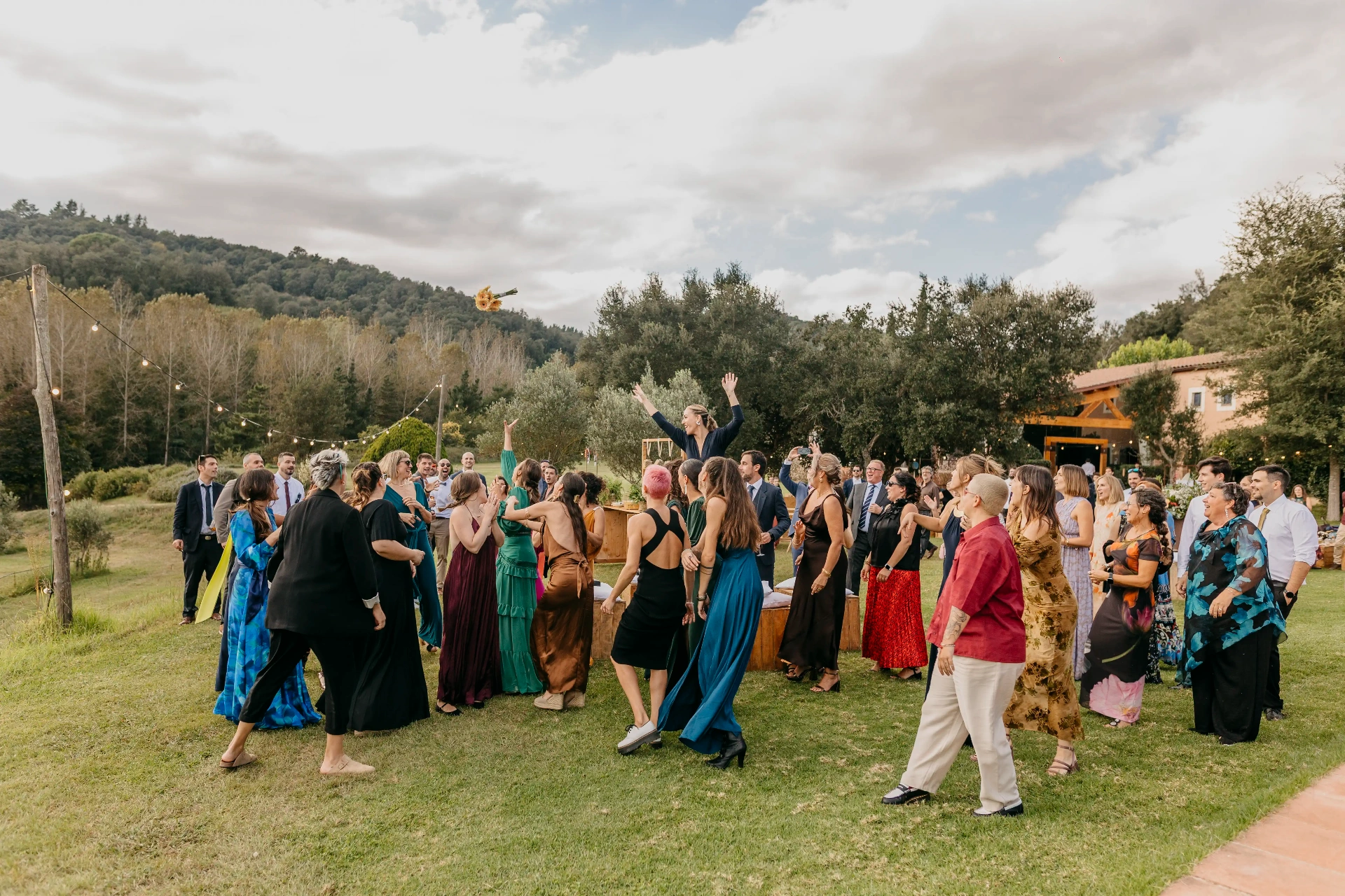 Momento del lanzamiento del ramo con el grupo de invitadas alrededor en los jardines de Can Riera de la Pineda