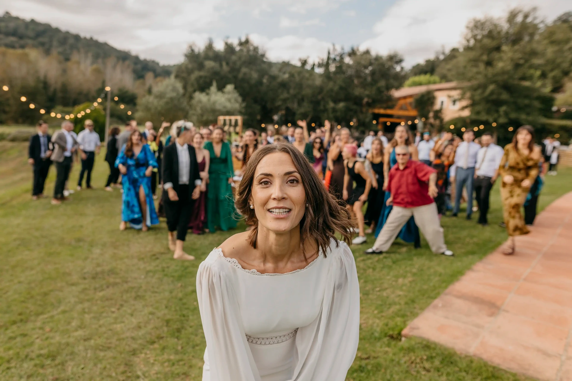 Retrato de Carla preparándose para lanzar el ramo con las invitadas al fondo en Can Riera de la Pineda