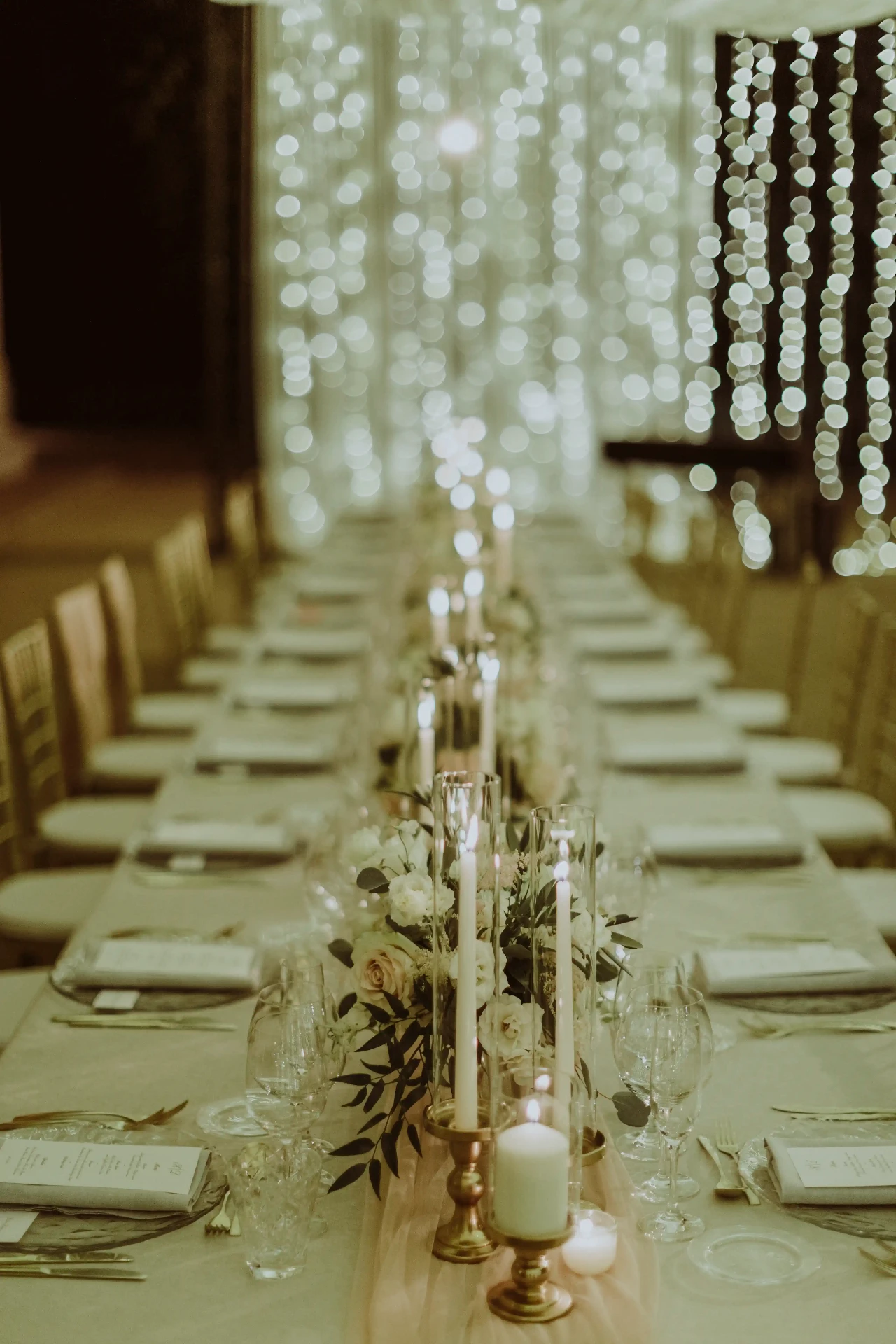 Mesa imperial iluminada con cortina de luces cálidas y candelabros dorados en el banquete de Bell Recó