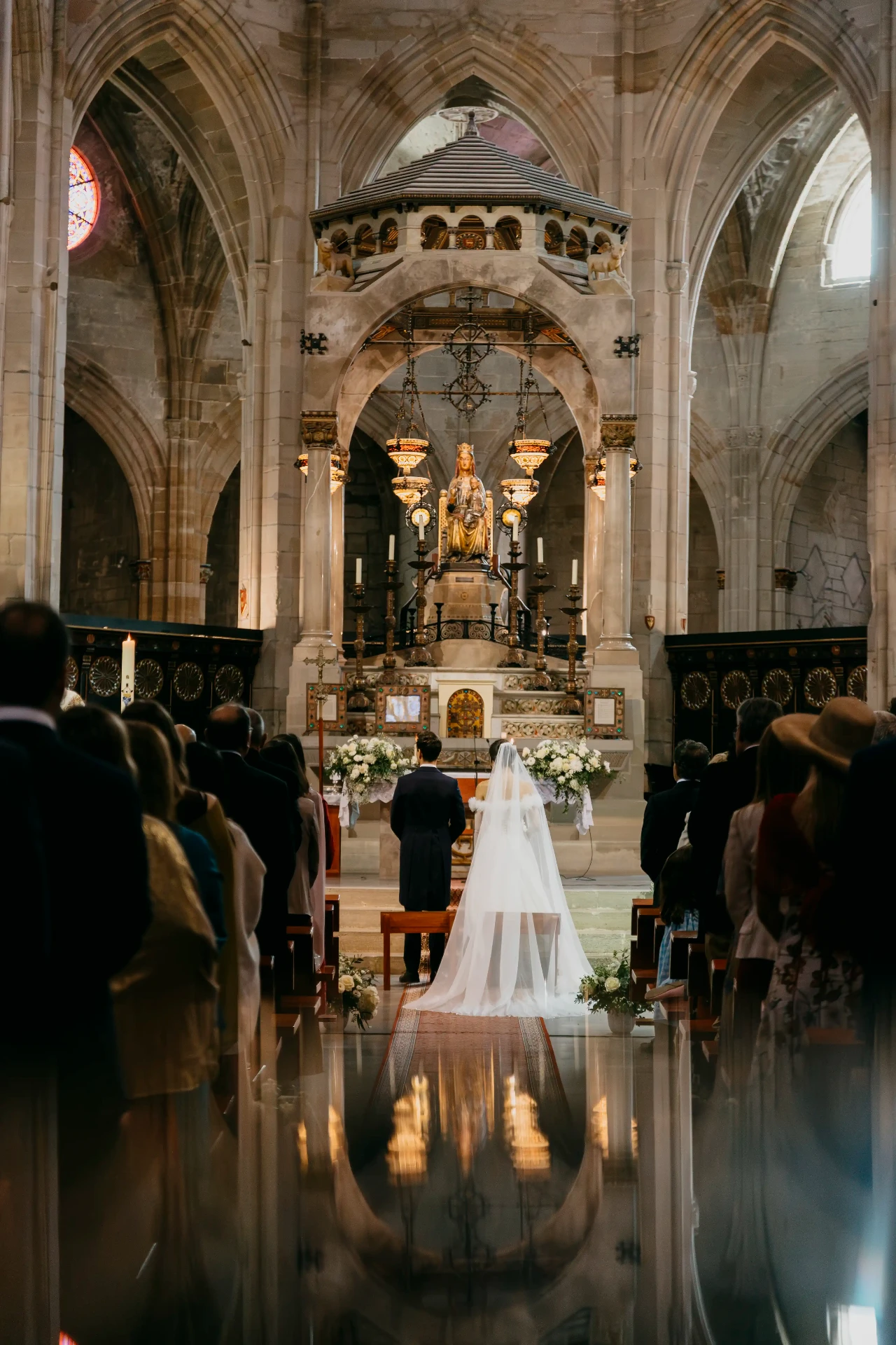 Novios de espaldas frente al altar mayor de Santa Maria de Cervera durante la ceremonia religiosa, boda Lleida