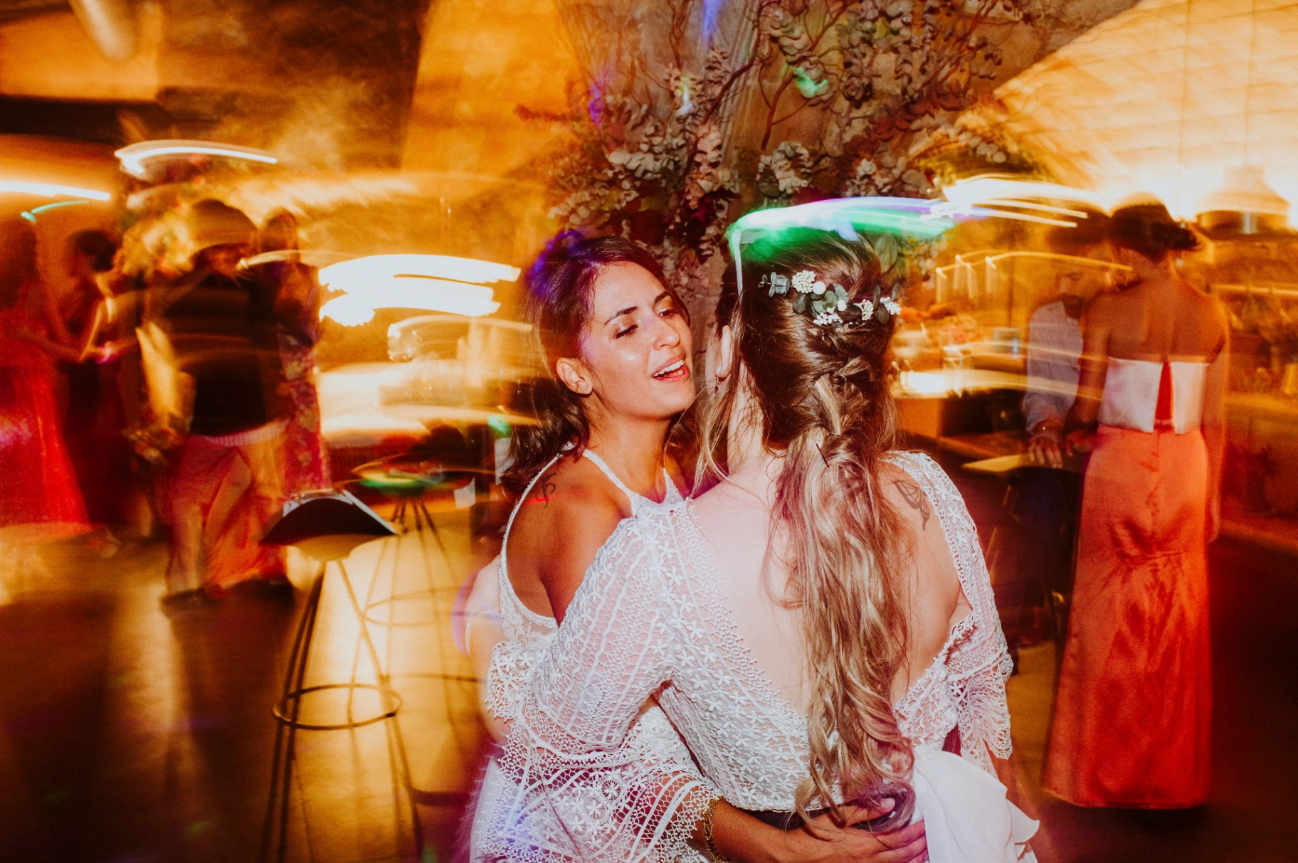 boda LGTBI en Ca n'Alzina — las novias abrazadas en la pista de baile con estelas de luces de colores durante la fiesta