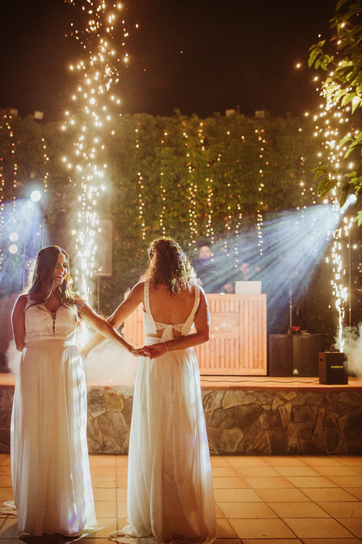 boda LGTBI en El Xaloc, Calders — primer baile de las novias de espaldas con fuentes de chispas y cortina de luces