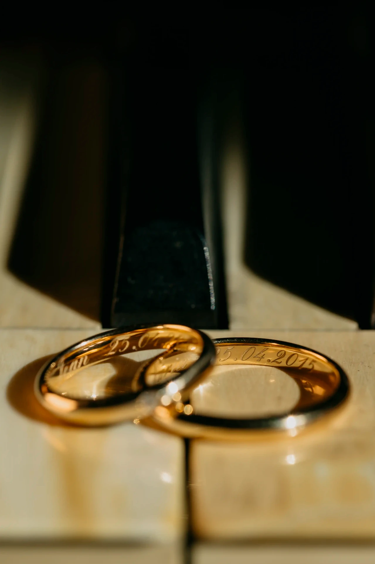 Detalle de anillos de boda grabados con fecha 25.04.2015 sobre piano, fotografía de detalles boda Lleida