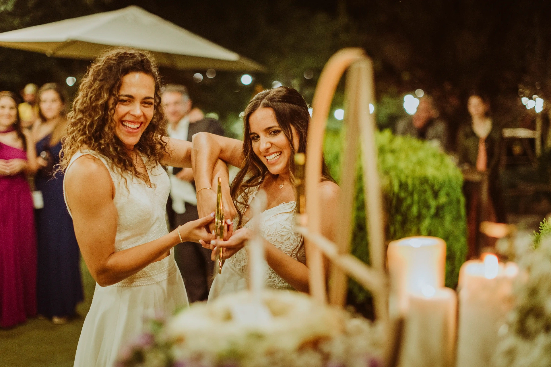 boda LGTBI en El Xaloc, Calders — las novias descorchan juntas una botella de cava entre risas