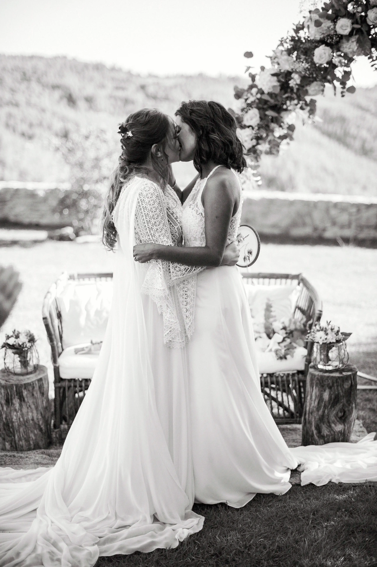 boda LGTBI en Ca n'Alzina (Rubió) — beso de las novias tras el sí quiero bajo el arco floral con las montañas al fondo