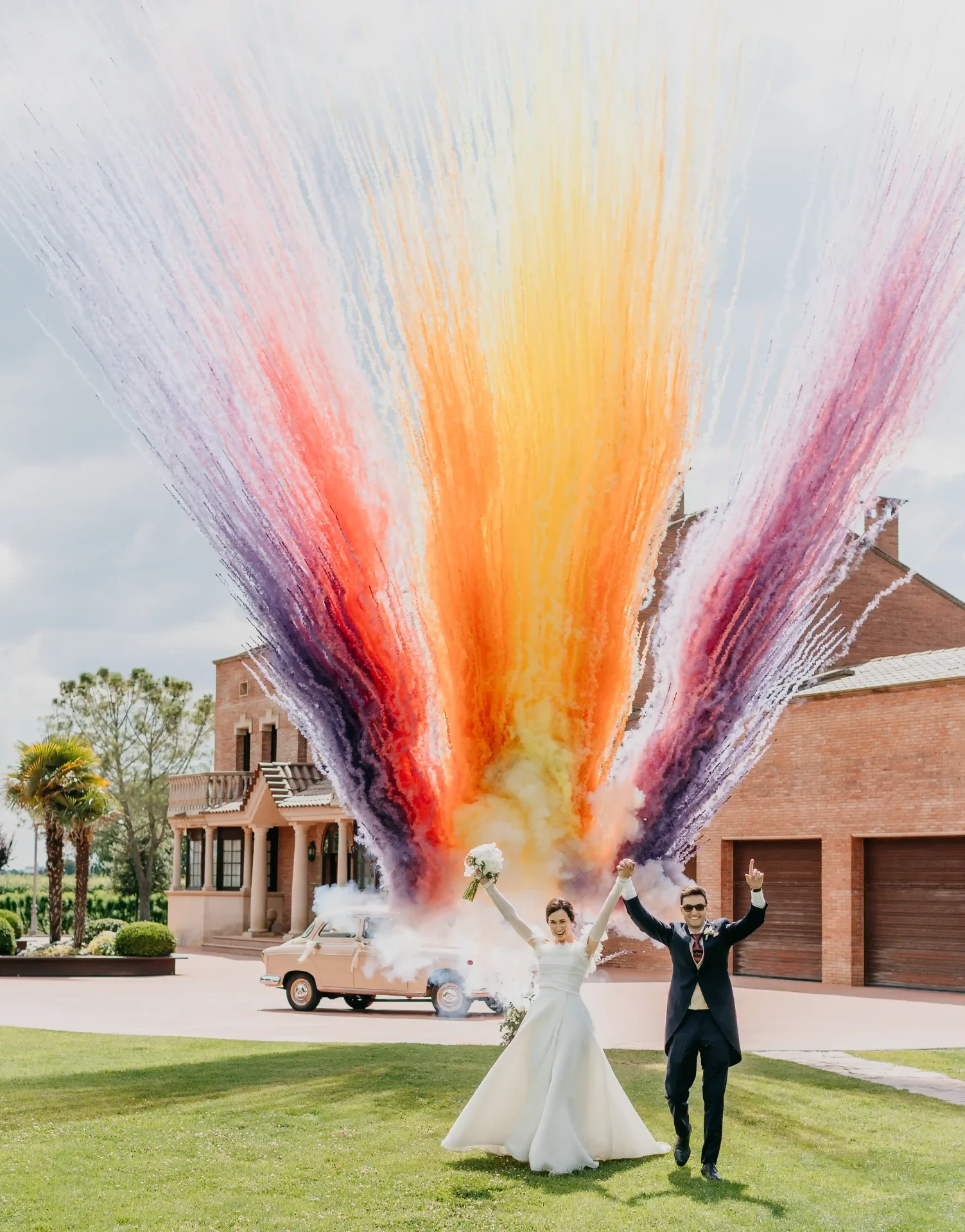 Recién casados celebrando con humos de colores frente a una masía en Catalunya. Piña Colada