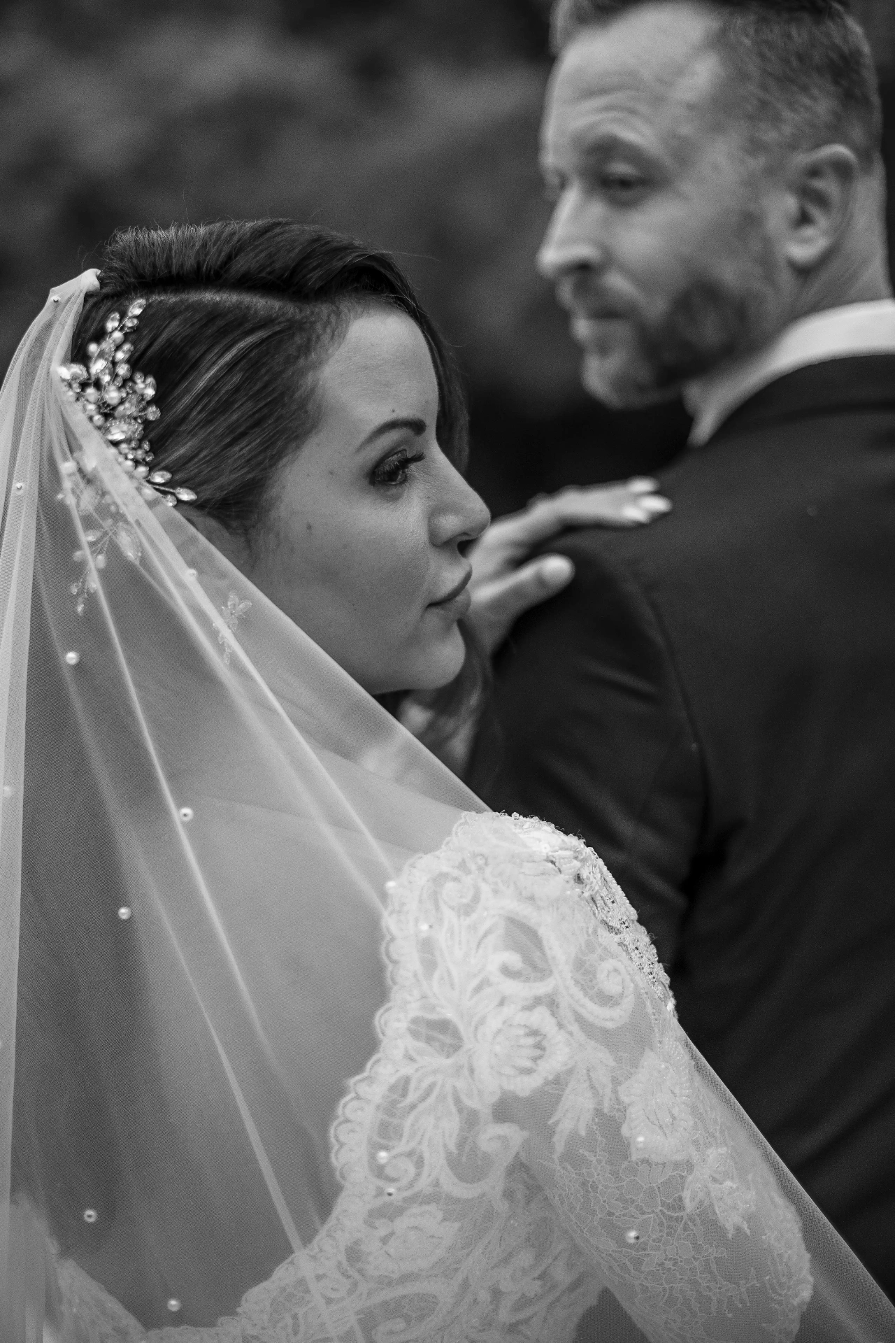 Retrato en blanco y negro de Ana abrazando a Lee con velo de perlas tras la ceremonia en Bell Recó