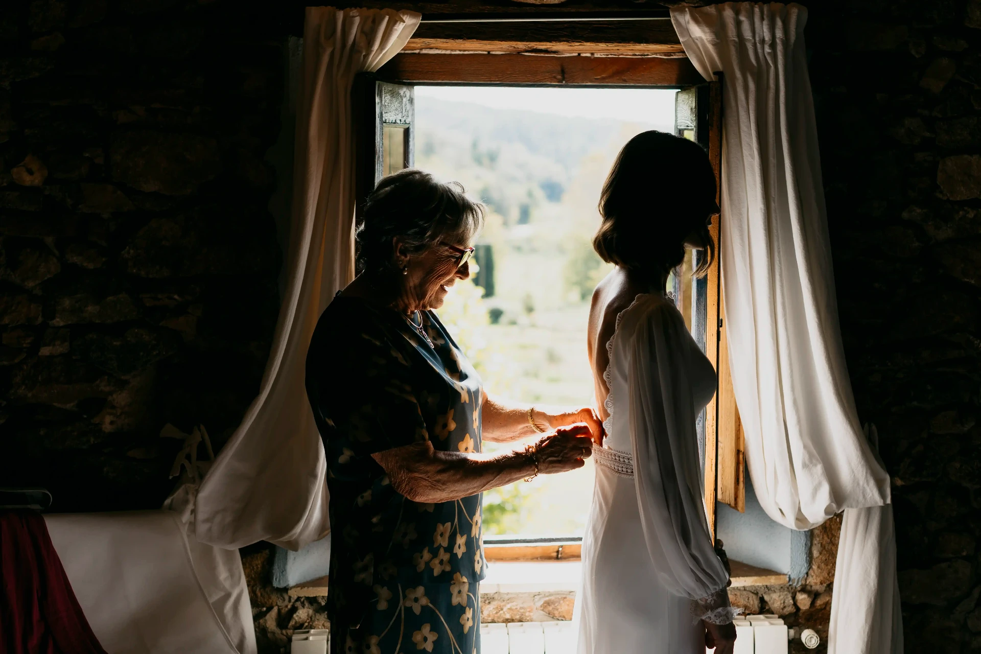 Madre ayudando a Carla con el vestido de novia en los preparativos en Can Riera de la Pineda