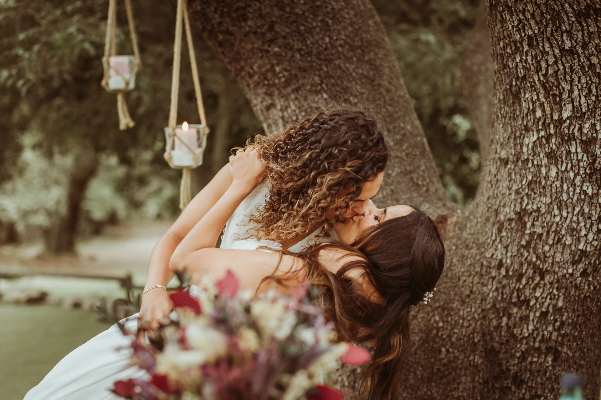 boda LGTBI en El Xaloc, Calders — beso apasionado de las novias inclinadas junto al árbol del altar