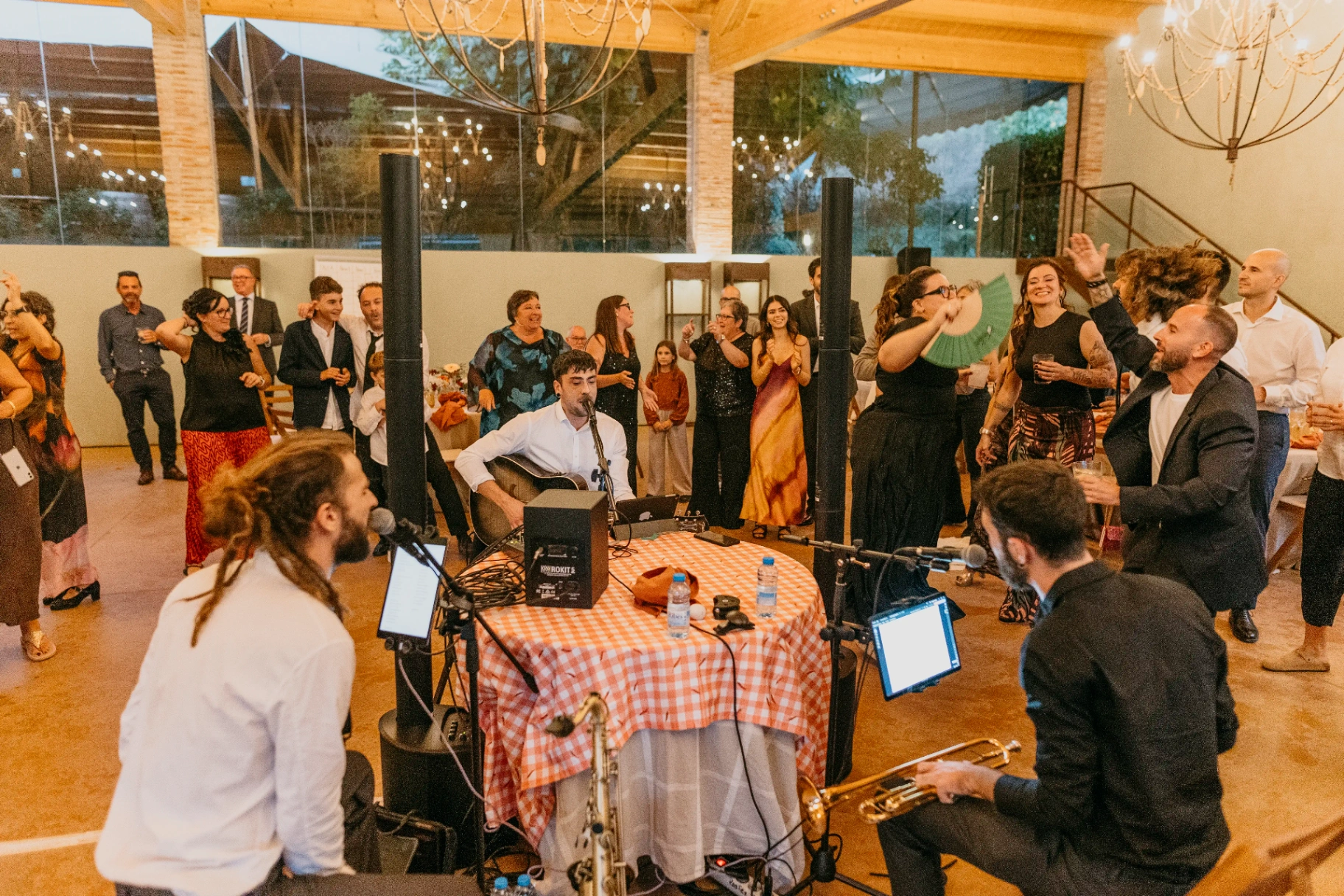 Concierto en directo con guitarra y trompeta rodeado de invitados bailando en la sala del banquete de Can Riera de la Pineda