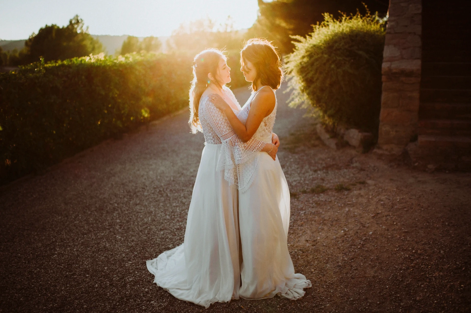 boda LGTBI en Ca n'Alzina (Rubió) — sesión de pareja de las novias abrazadas a contraluz al atardecer