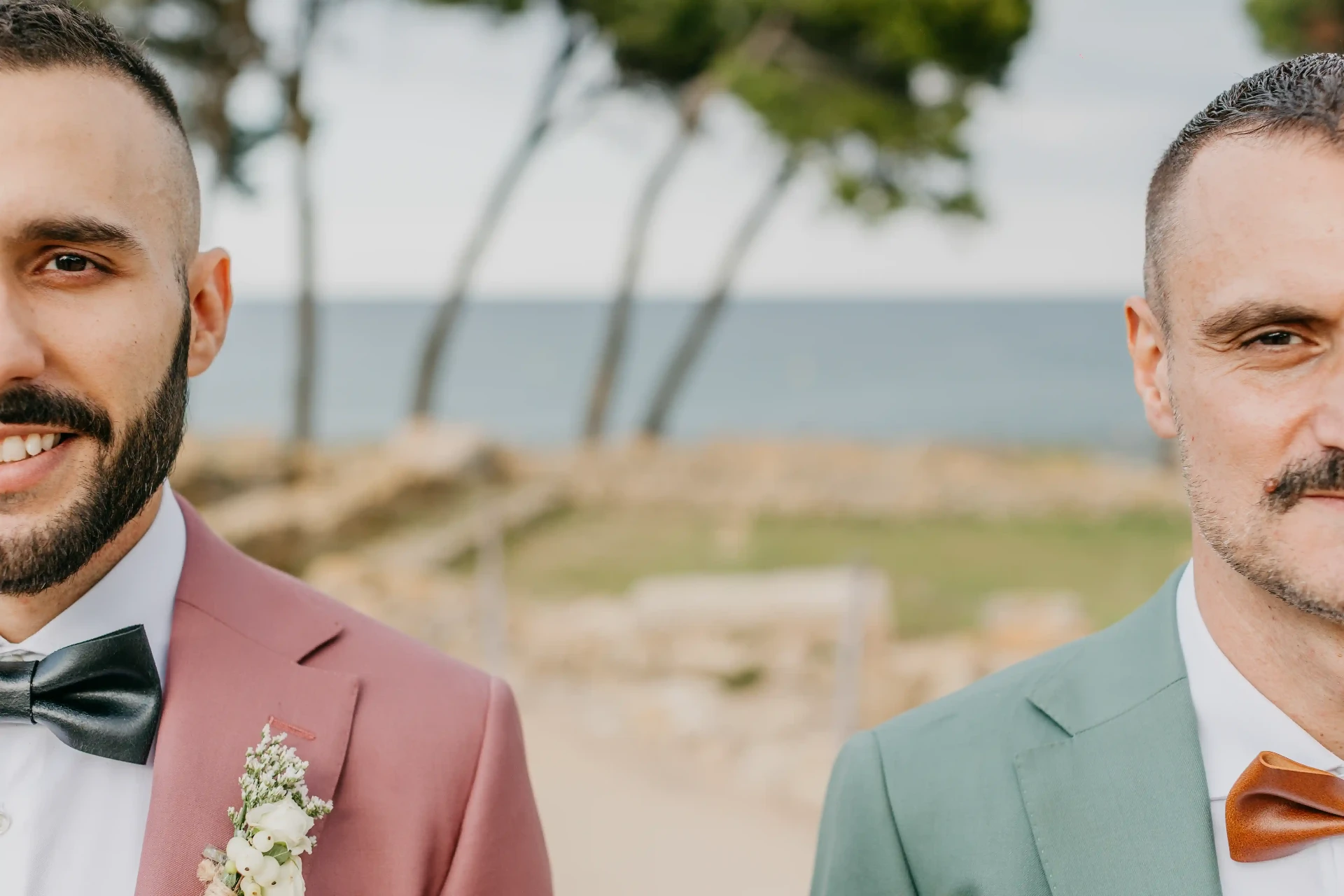 Boda gay en Mas Terrats Barcelona — dos novios sonrientes junto al mar