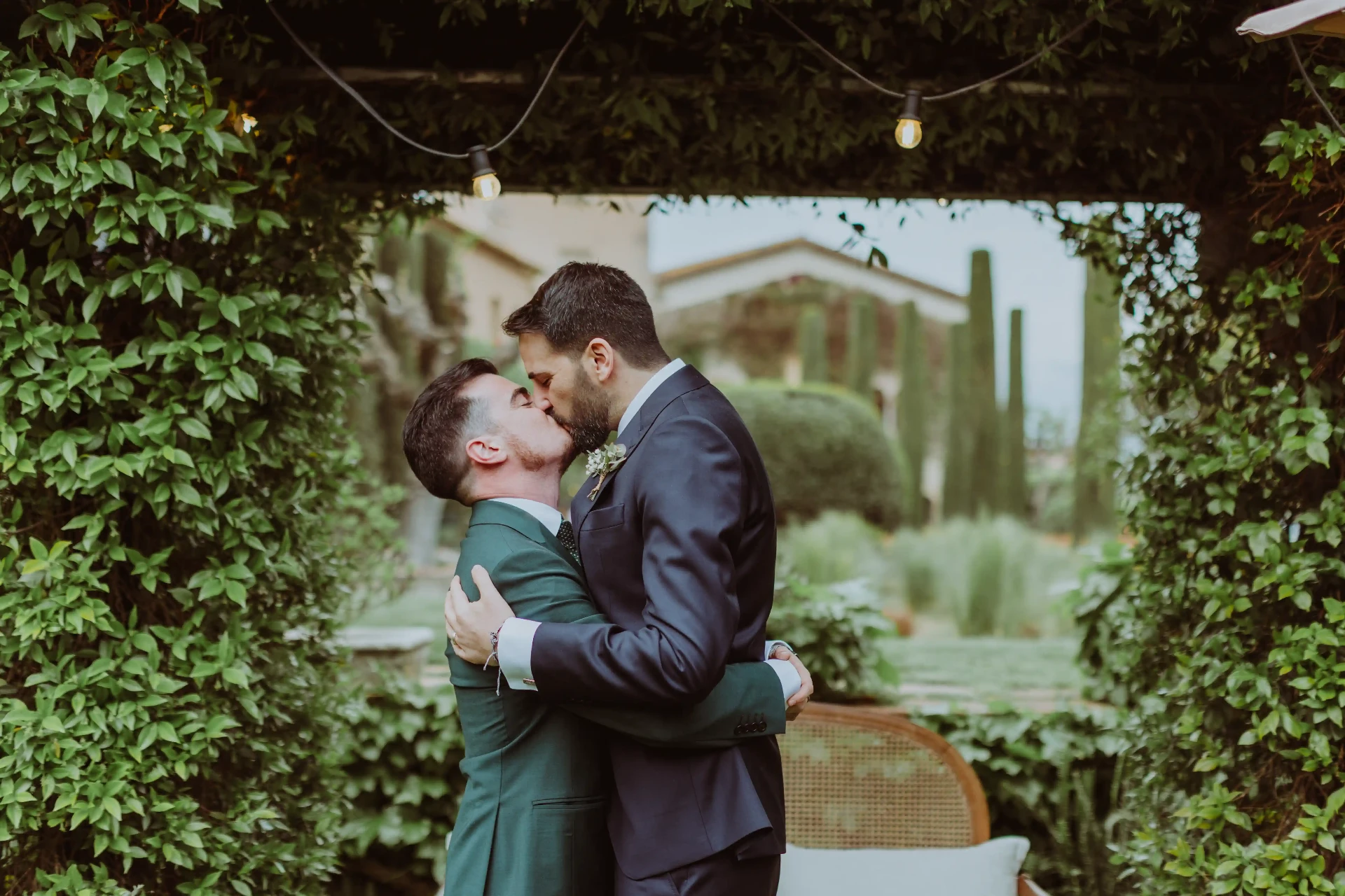 boda LGTBI en Can Ribas — beso de los novios bajo el arco de hiedra