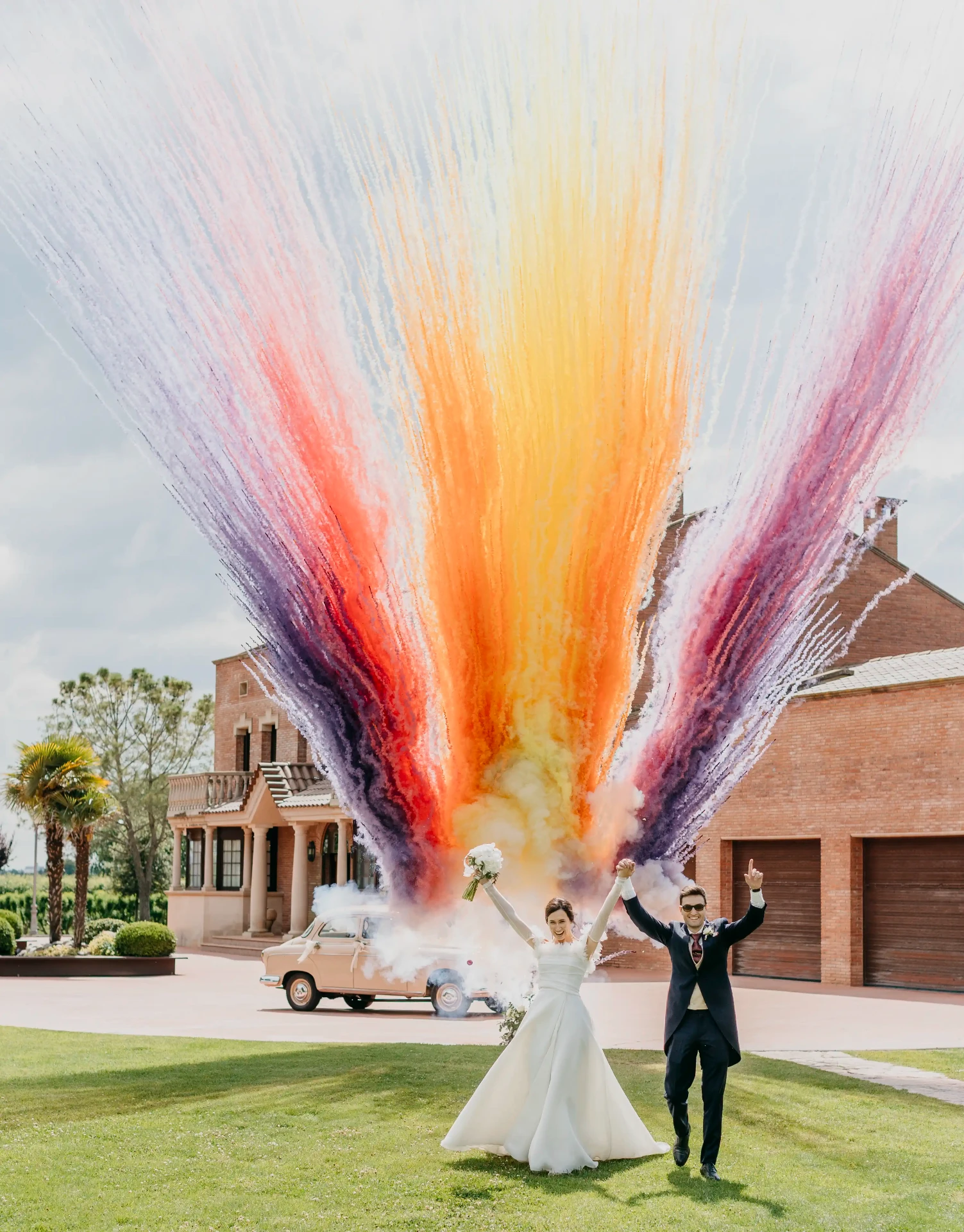 Joan y Núria celebrando con explosión de humos de colores a la salida de la ceremonia en La Boscana, boda en Bellvís (Lleida) por fotógrafo de bodas