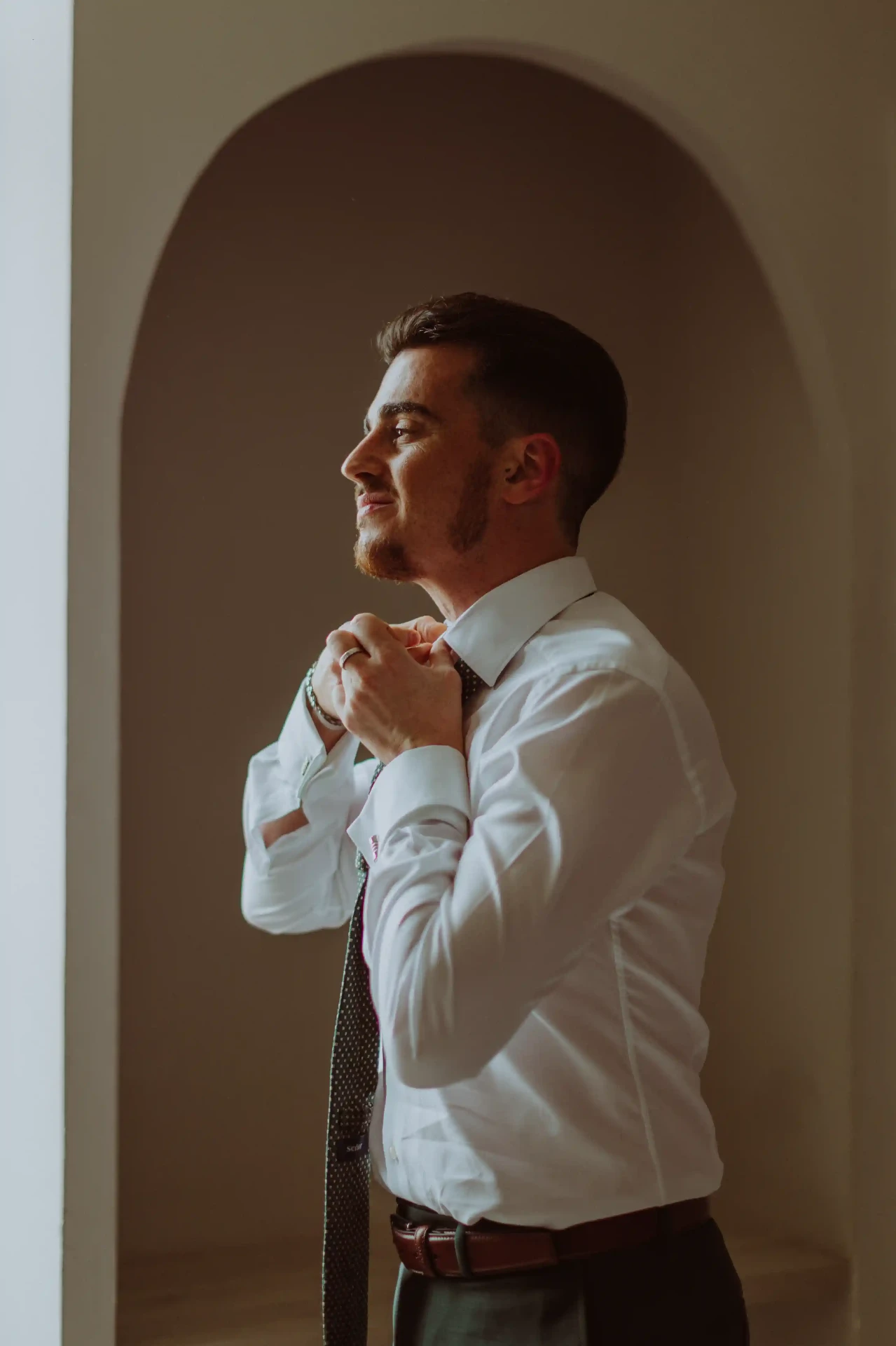 boda LGTBI en Can Ribas — novio ajustándose la corbata bajo un arco