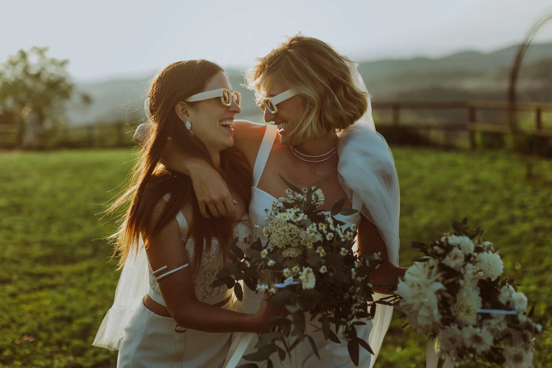 Novias riendo con gafas de sol y ramos al atardecer — boda en This Must Be The Place por Piña Colada Studio