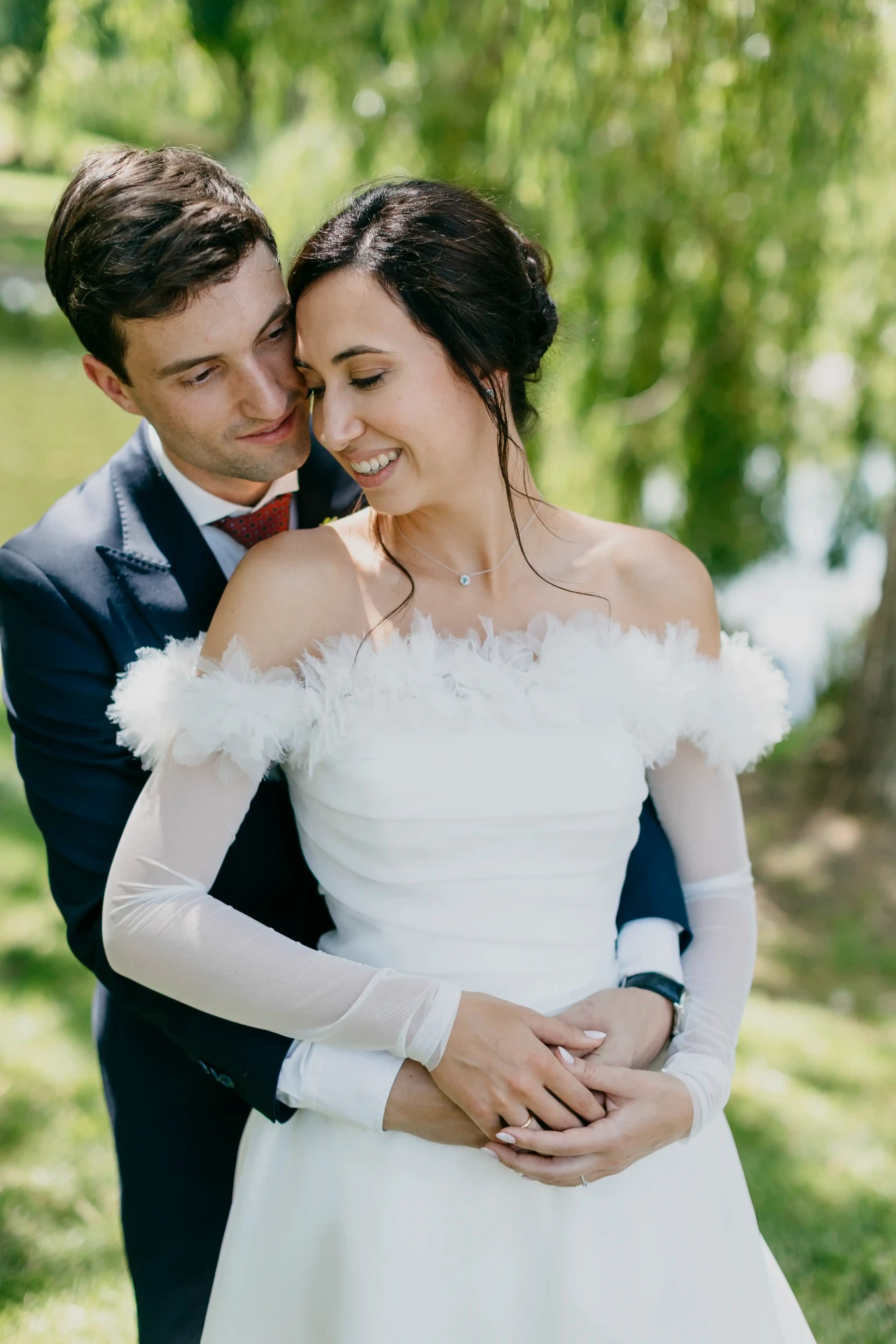 Novio abrazando a Núria por detrás bajo un sauce llorón en los jardines de La Boscana, retrato boda Bellvís Lleida
