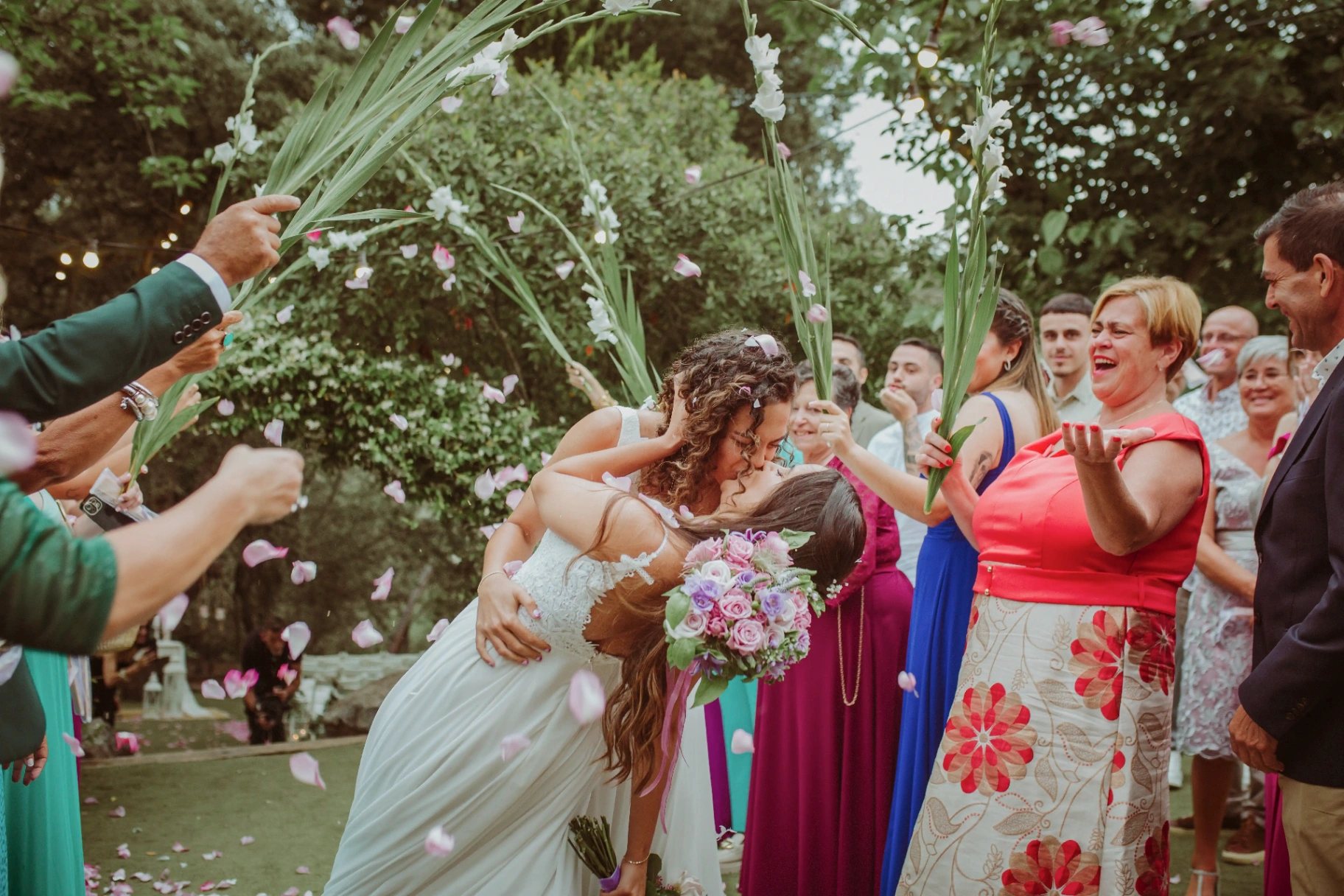 boda LGTBI en El Xaloc, Calders — beso de las novias bajo una lluvia de pétalos a la salida de la ceremonia