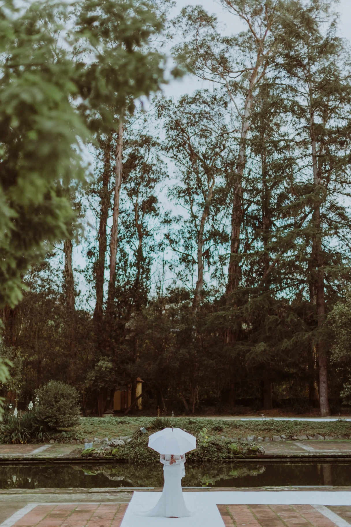 Novia de espaldas con paraguas blanco frente al bosque de Bell Recó Argentona por fotógrafo de bodas Barcelona