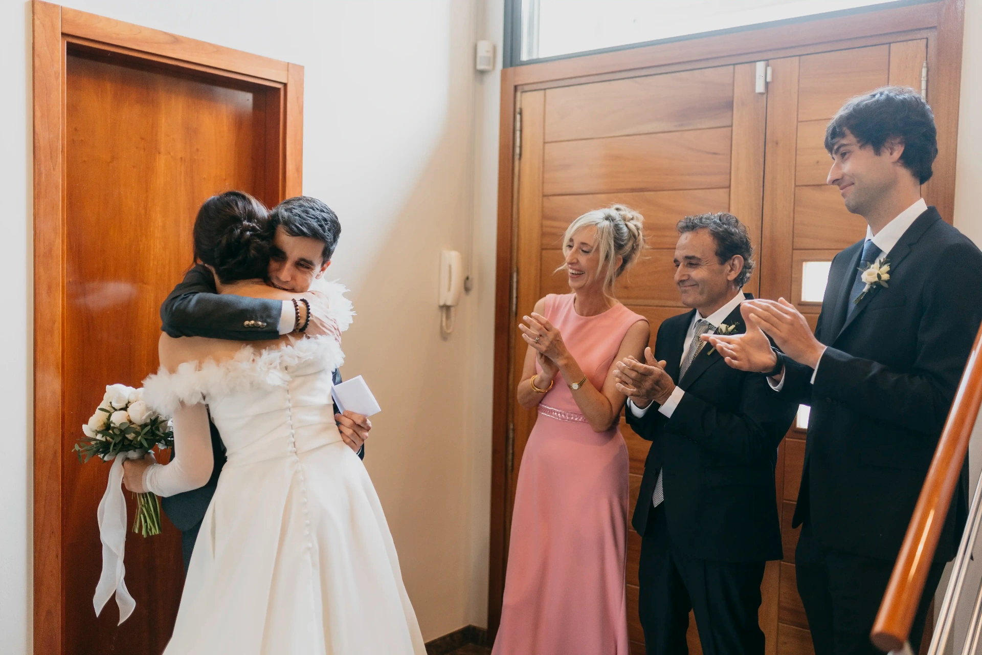 Novios abrazándose en la entrada de casa mientras la familia aplaude emocionada, boda en Cervera y La Boscana Lleida