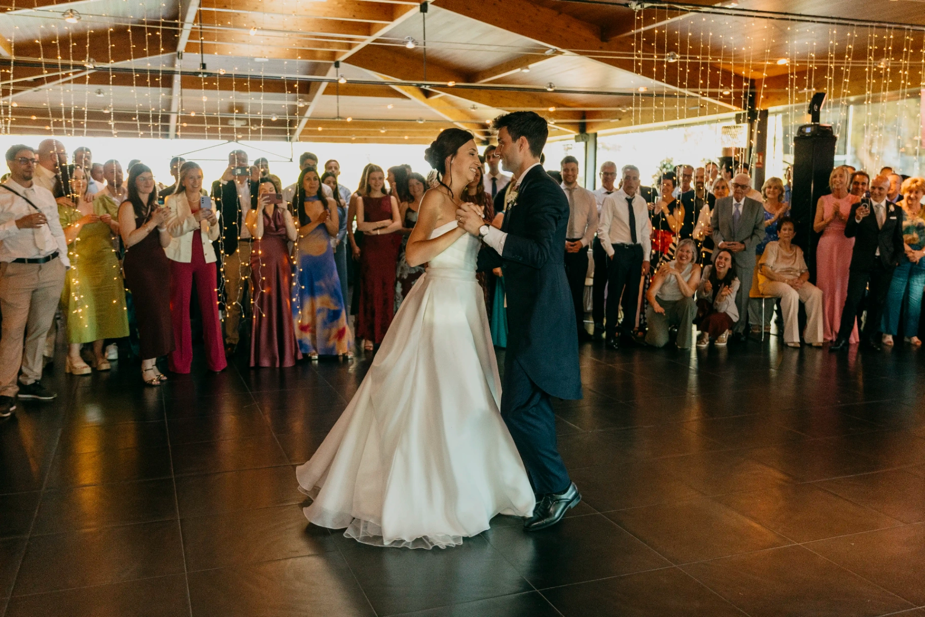 Primer baile de Joan y Núria en la pista rodeados por los invitados bajo cortinas de luces, boda La Boscana Lleida
