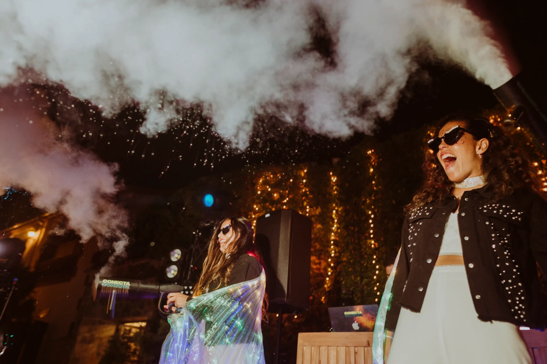 boda LGTBI en El Xaloc, Calders — las novias en la cabina del DJ entre nubes de humo y confeti durante la fiesta