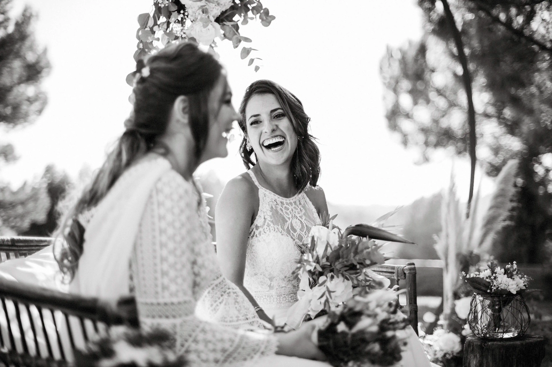 boda LGTBI en Ca n'Alzina — retrato en blanco y negro de las novias riendo bajo el arco floral