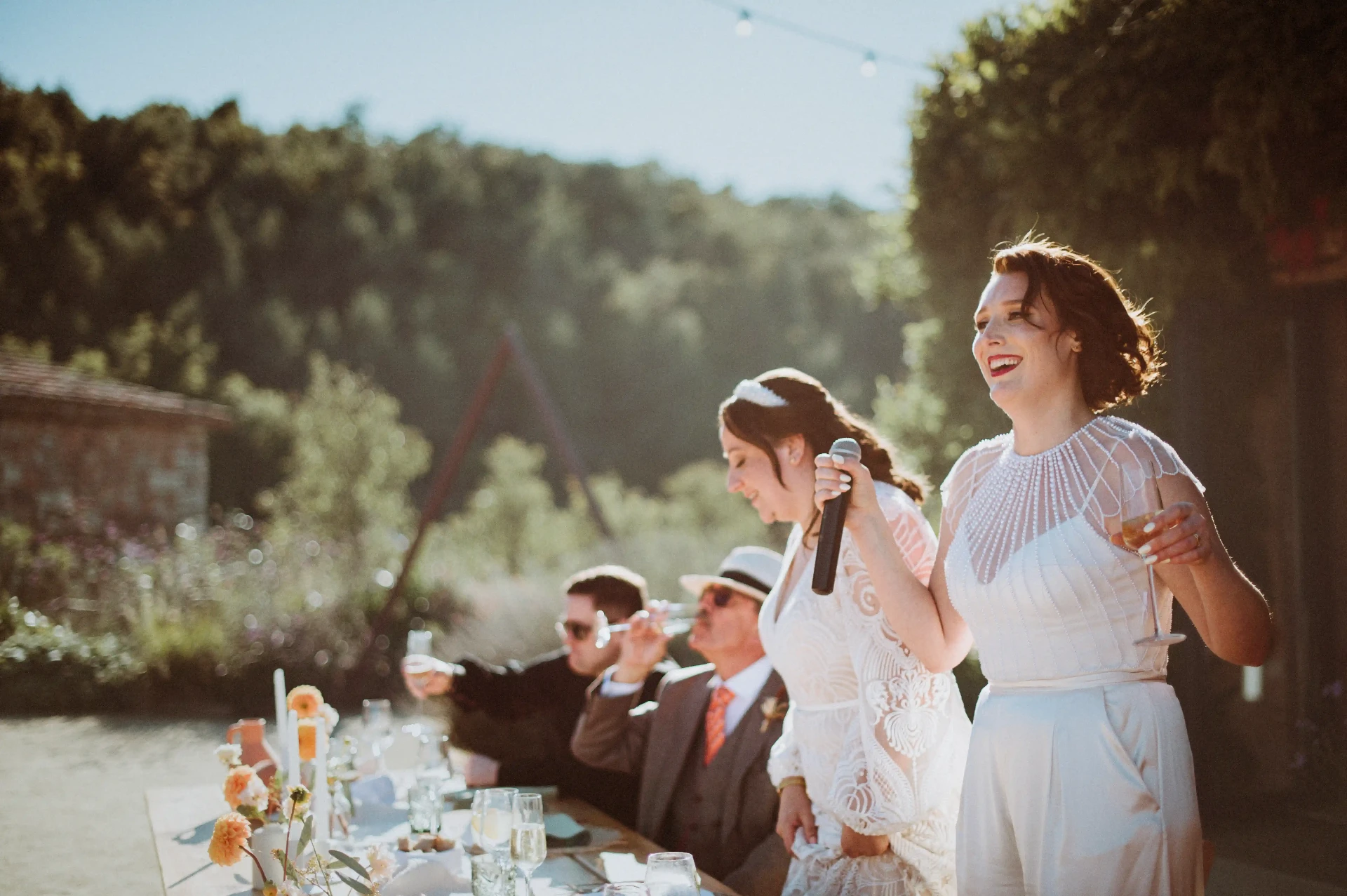 Discurso de las novias durante el aperitivo al aire libre con guirnaldas de luces en This Must Be The Place