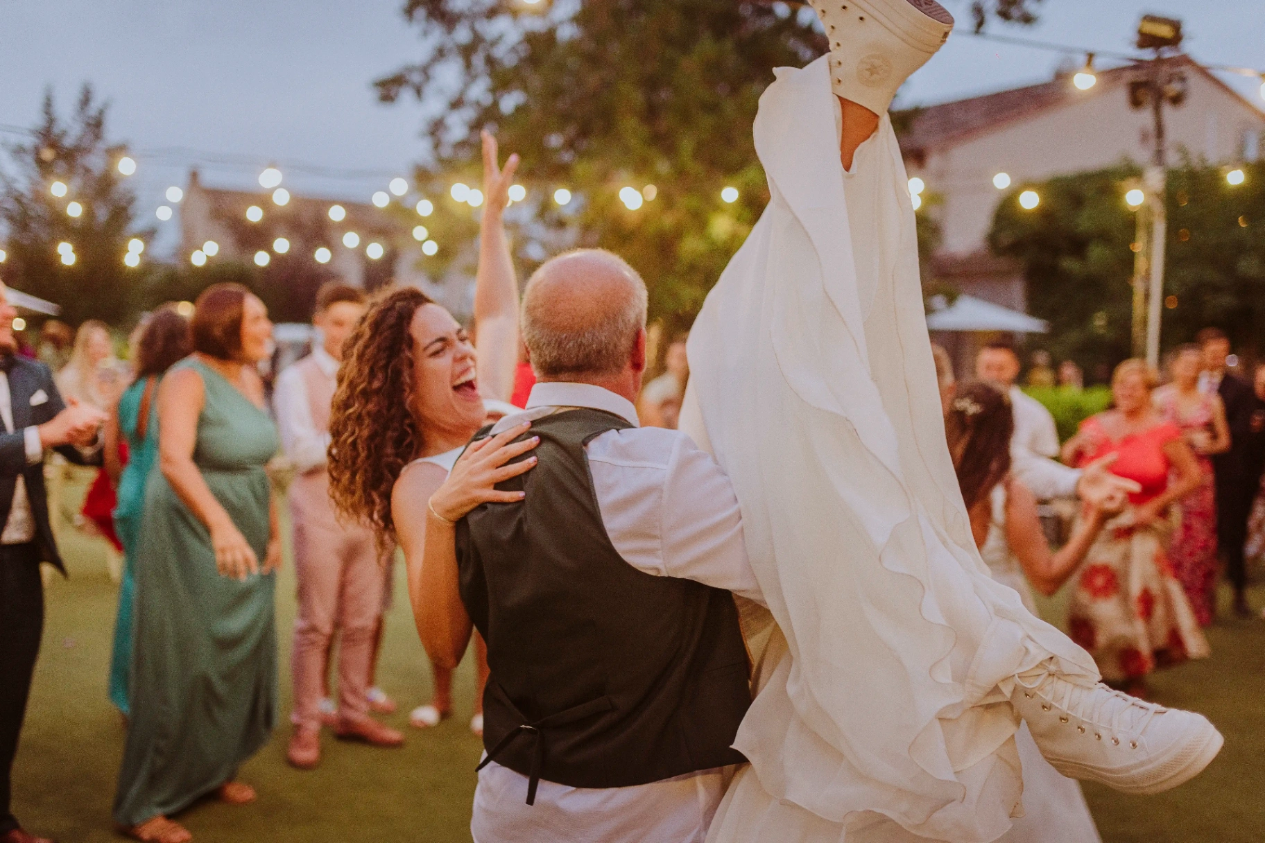 boda LGTBI en El Xaloc, Calders — un invitado levanta a una novia en volandas mientras la otra celebra riendo