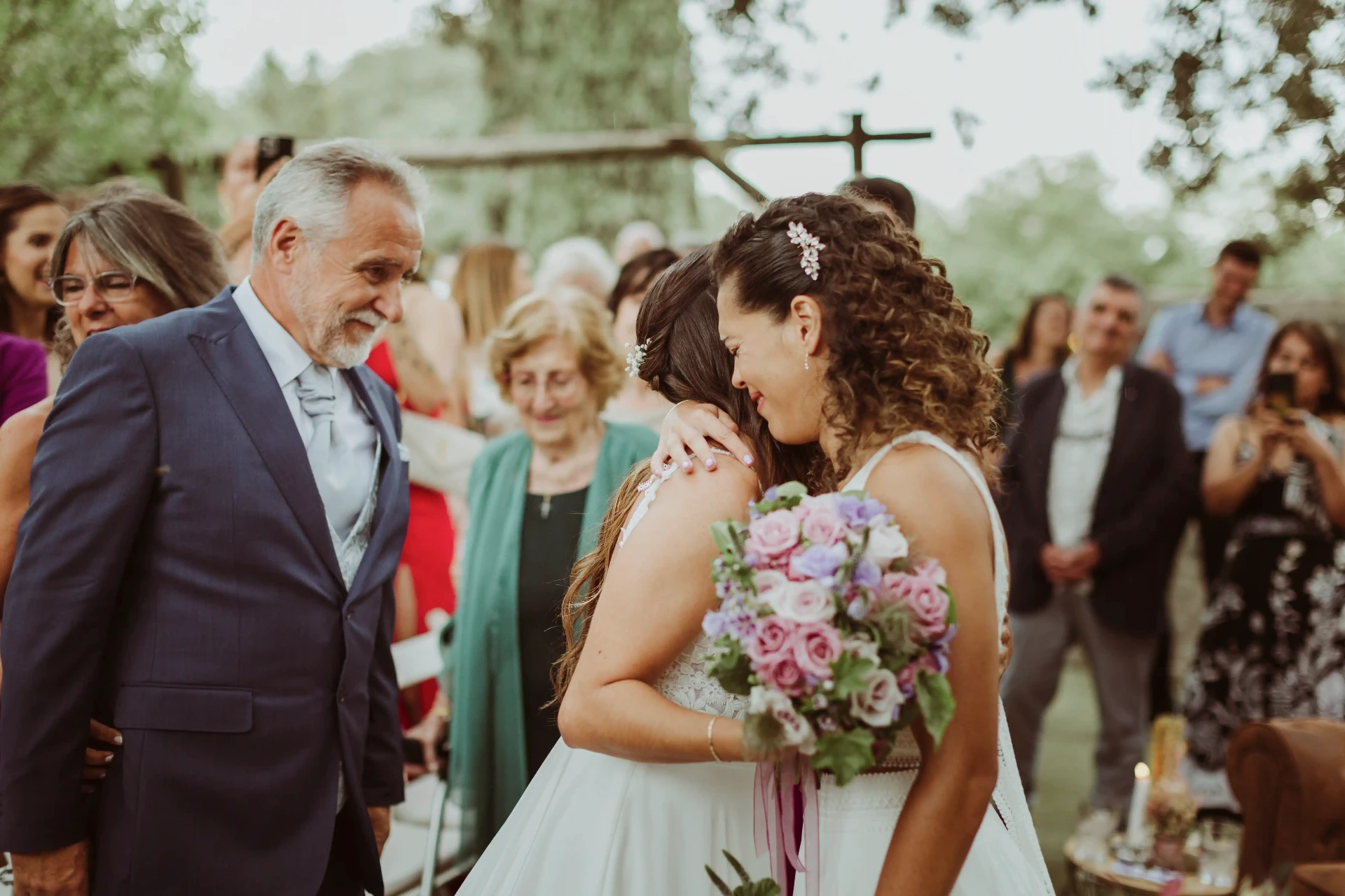 boda LGTBI en El Xaloc, Calders — las novias se abrazan en el altar durante la ceremonia en el jardín