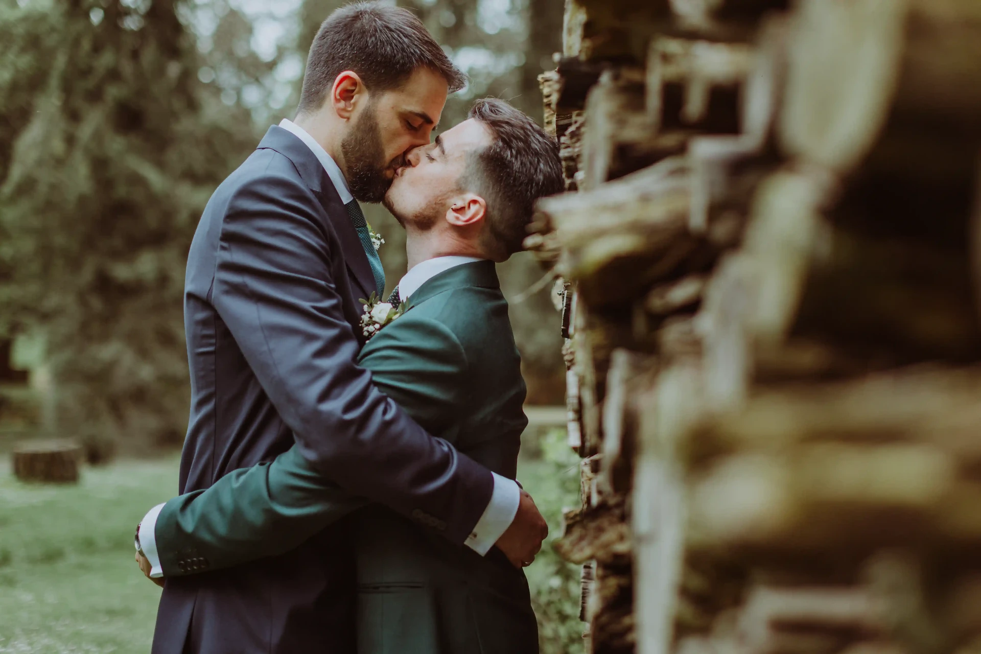 boda LGTBI en Can Ribas — beso íntimo de los novios junto a la leñera del bosque
