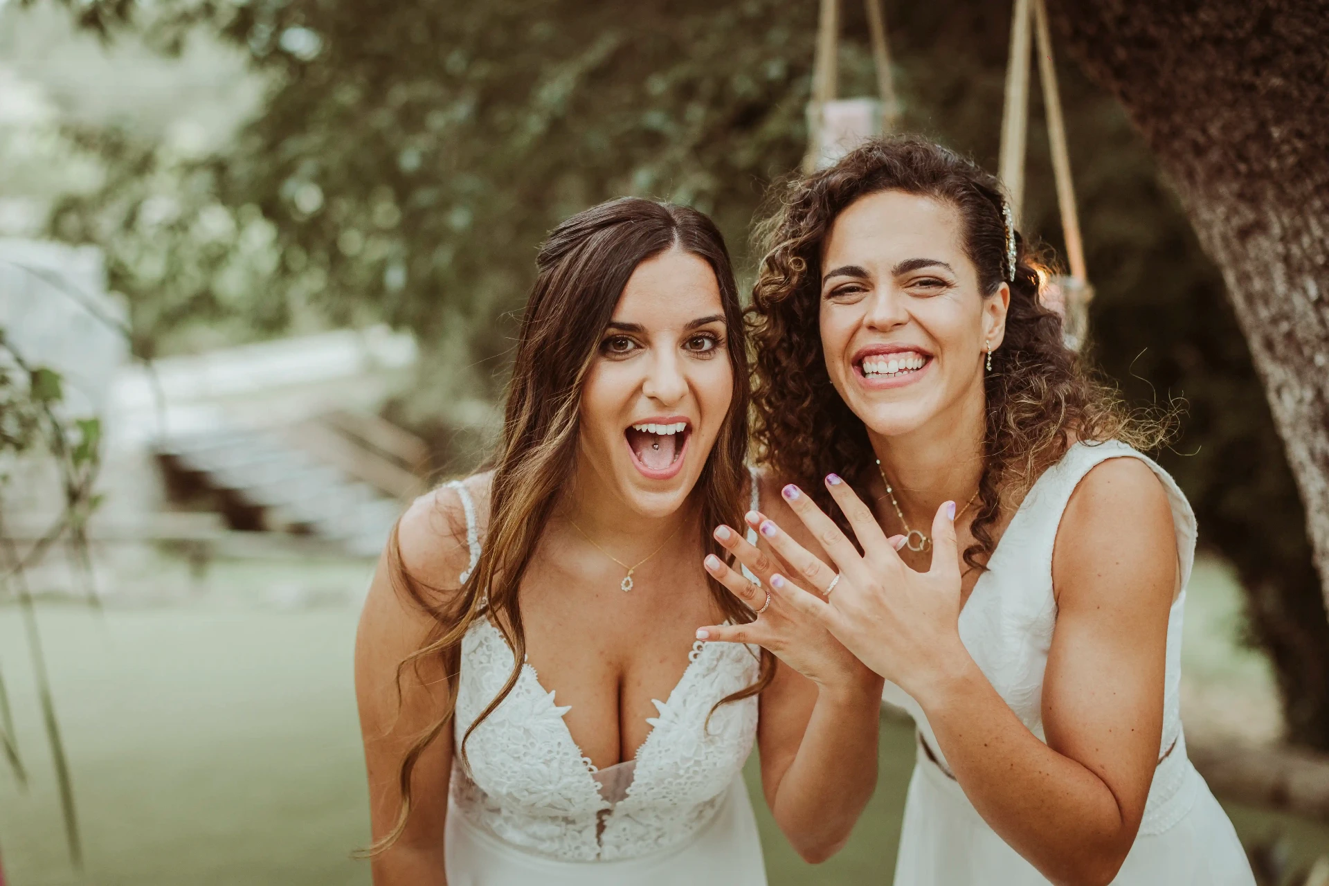 boda LGTBI en El Xaloc, Calders — las novias enseñan las alianzas mirando a cámara con complicidad