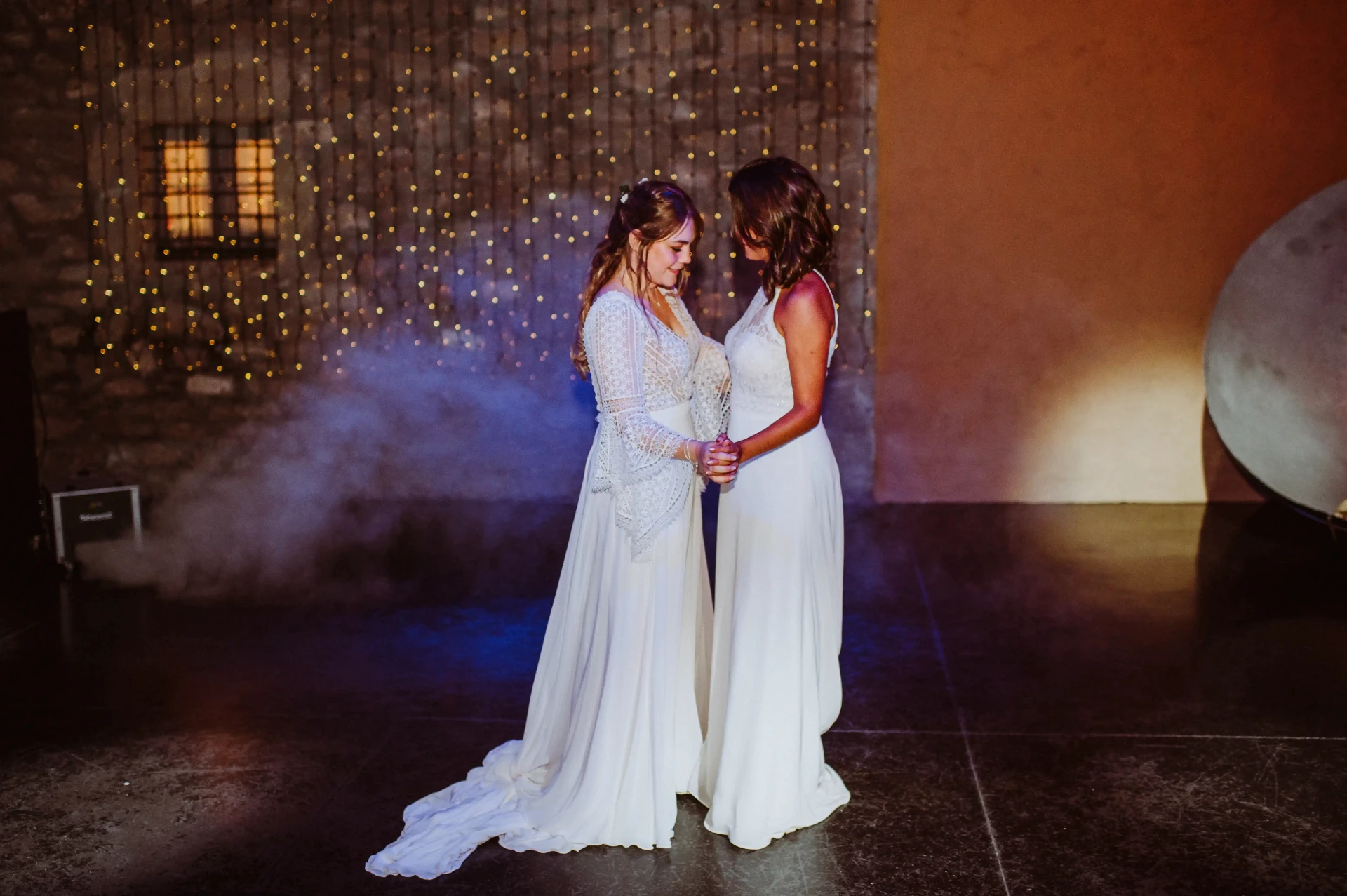 boda LGTBI en Ca n'Alzina (Rubió) — primer baile de las novias sobre la pista con humo y cortina de luces al fondo