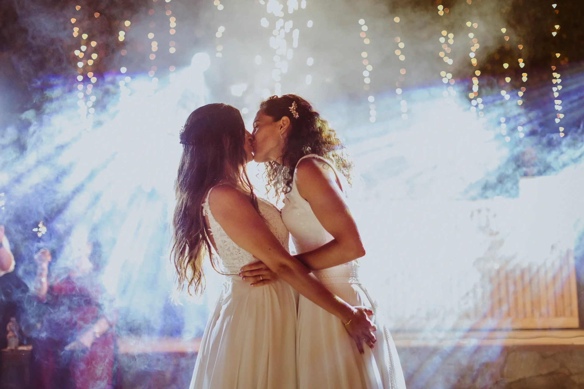 boda LGTBI en El Xaloc, Calders — beso íntimo de las novias en el primer baile entre luces y humo