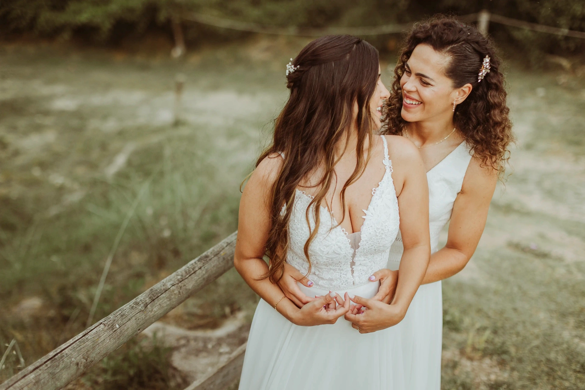 boda LGTBI en El Xaloc, Calders — una novia abraza por detrás a la otra en el paisaje del Moianès