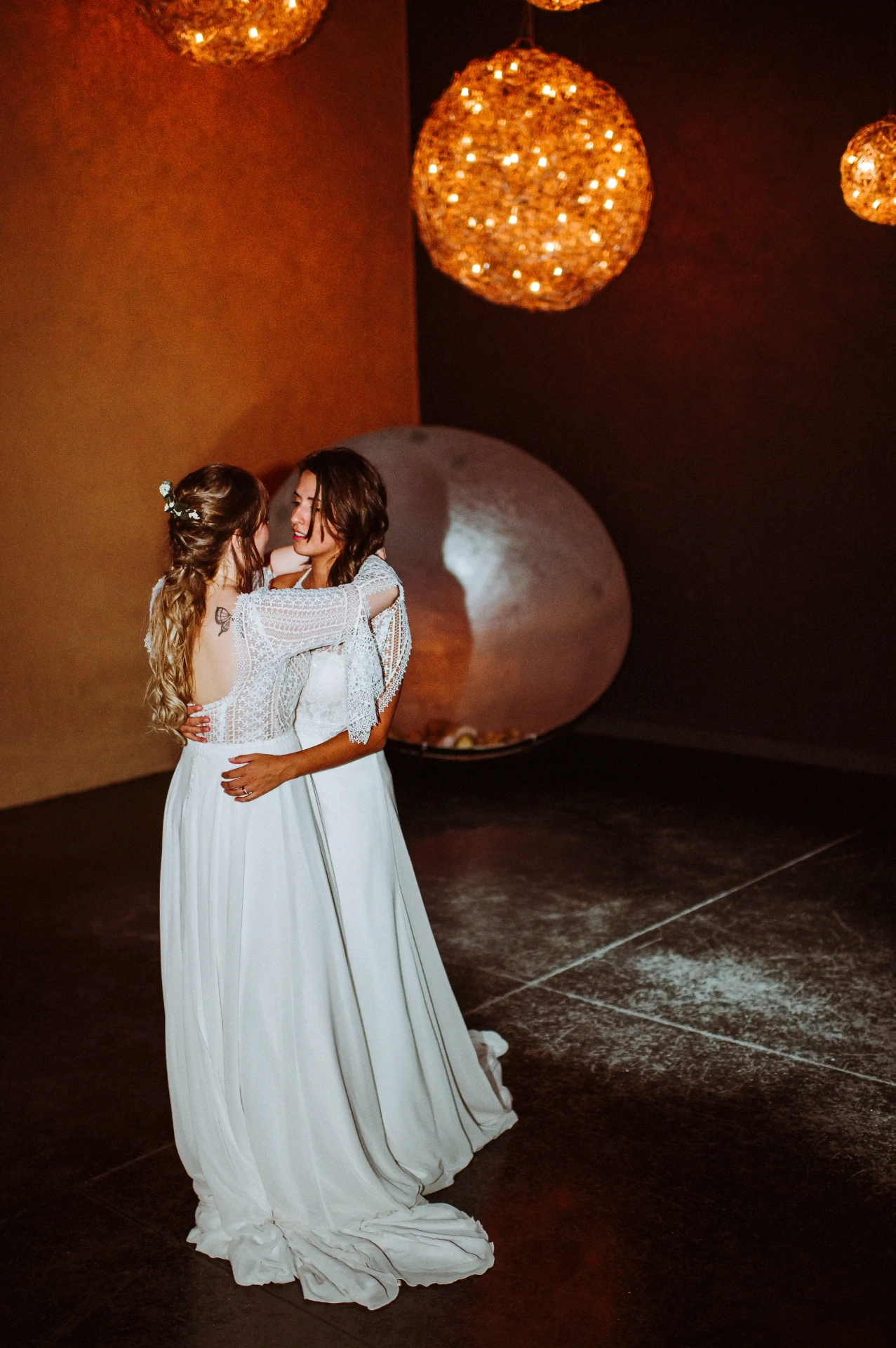 boda LGTBI en Ca n'Alzina — las novias abrazadas en el primer baile bajo las lámparas de mimbre