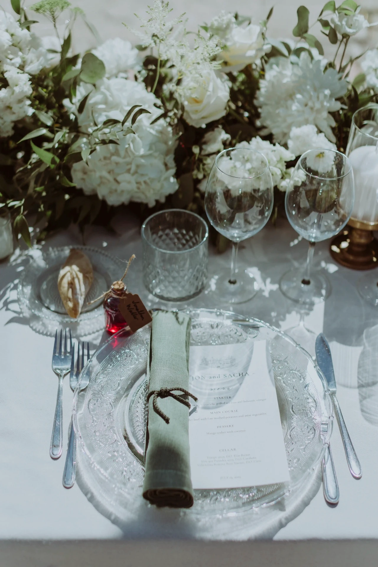 Detalle de la mesa del banquete con flores blancas y menú Jon and Sacha en La Baronia