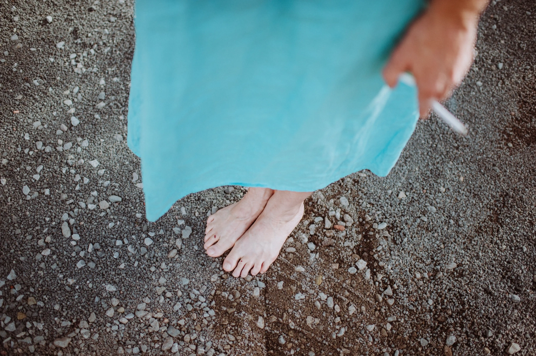 Detalle del vestido azul y los pies descalzos de una invitada sobre la gravilla en This Must Be The Place