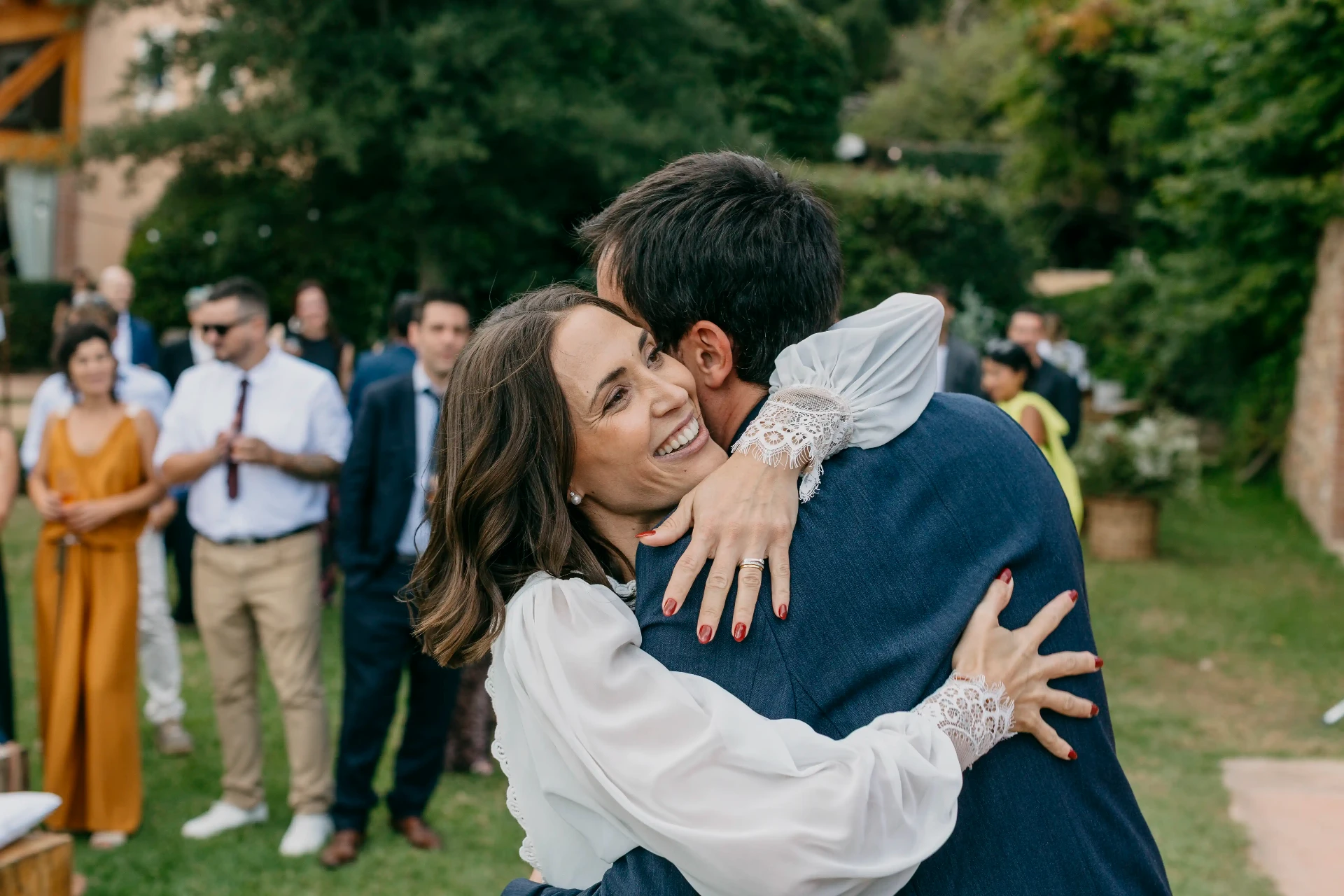 Abrazo emotivo de Carla con un invitado durante el aperitivo en los jardines de Can Riera de la Pineda