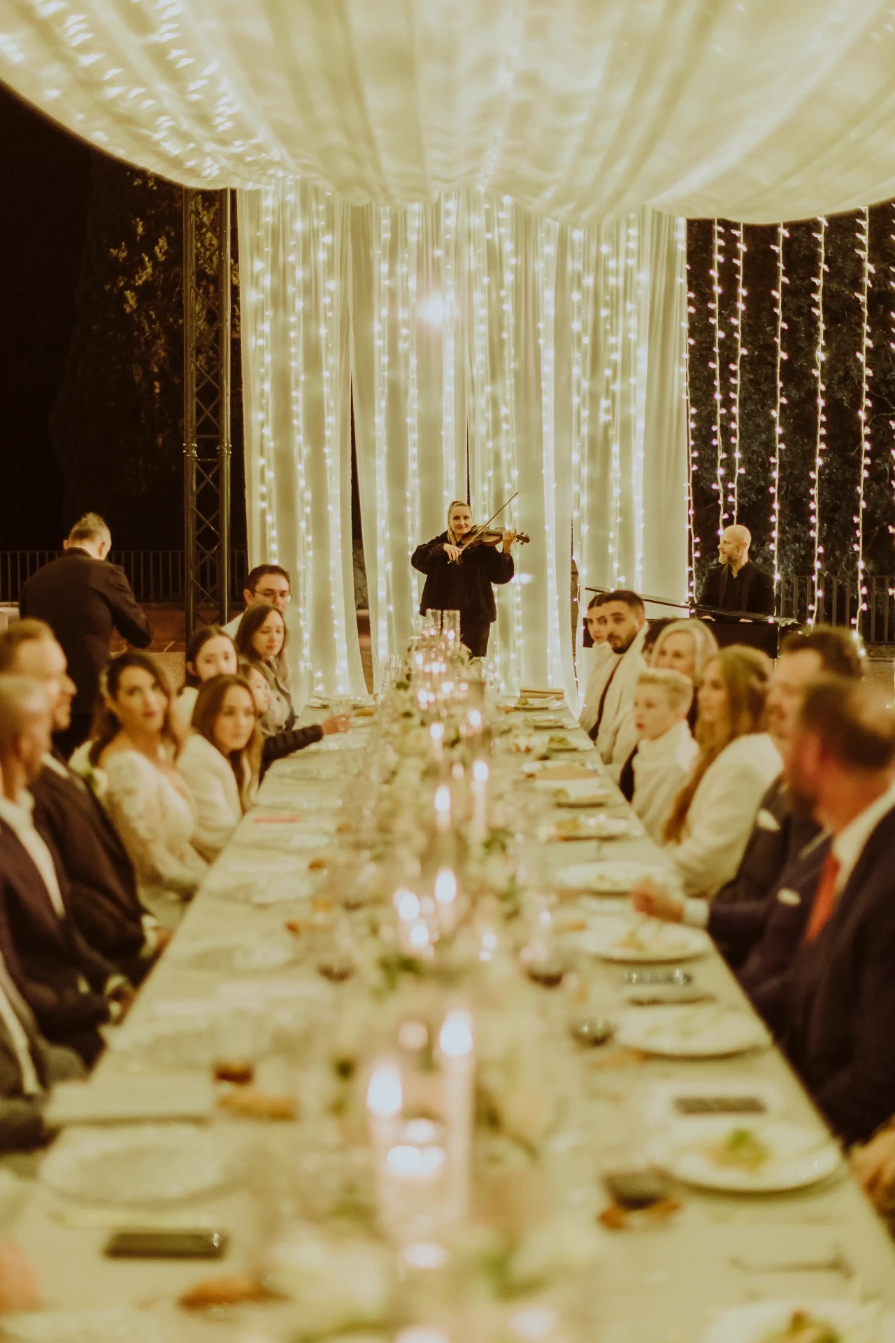 Violinista y pianista en directo durante la cena de boda entre cortinas de luces en Bell Recó