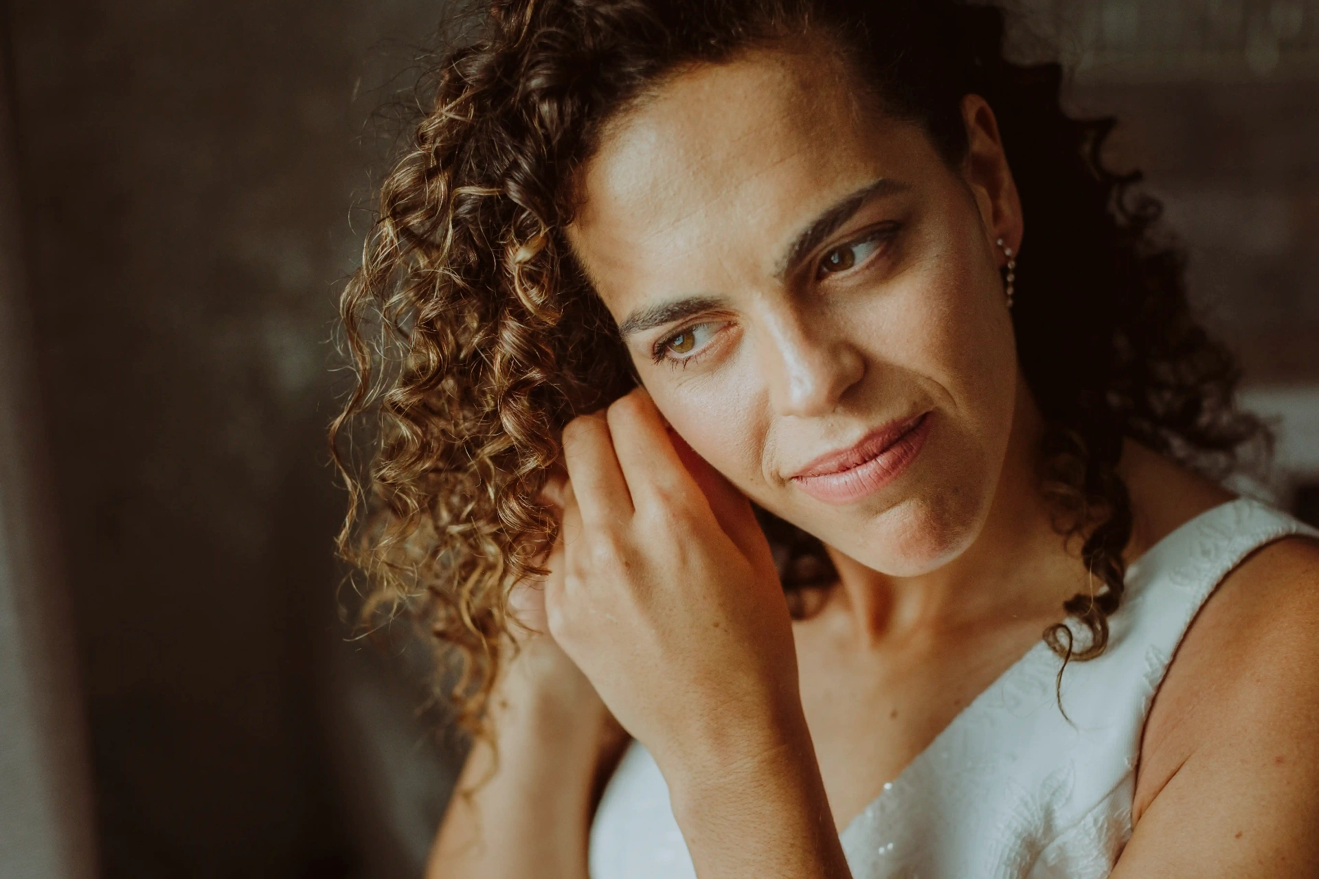 boda LGTBI en El Xaloc, Calders — retrato de una novia de pelo rizado ajustándose el pendiente