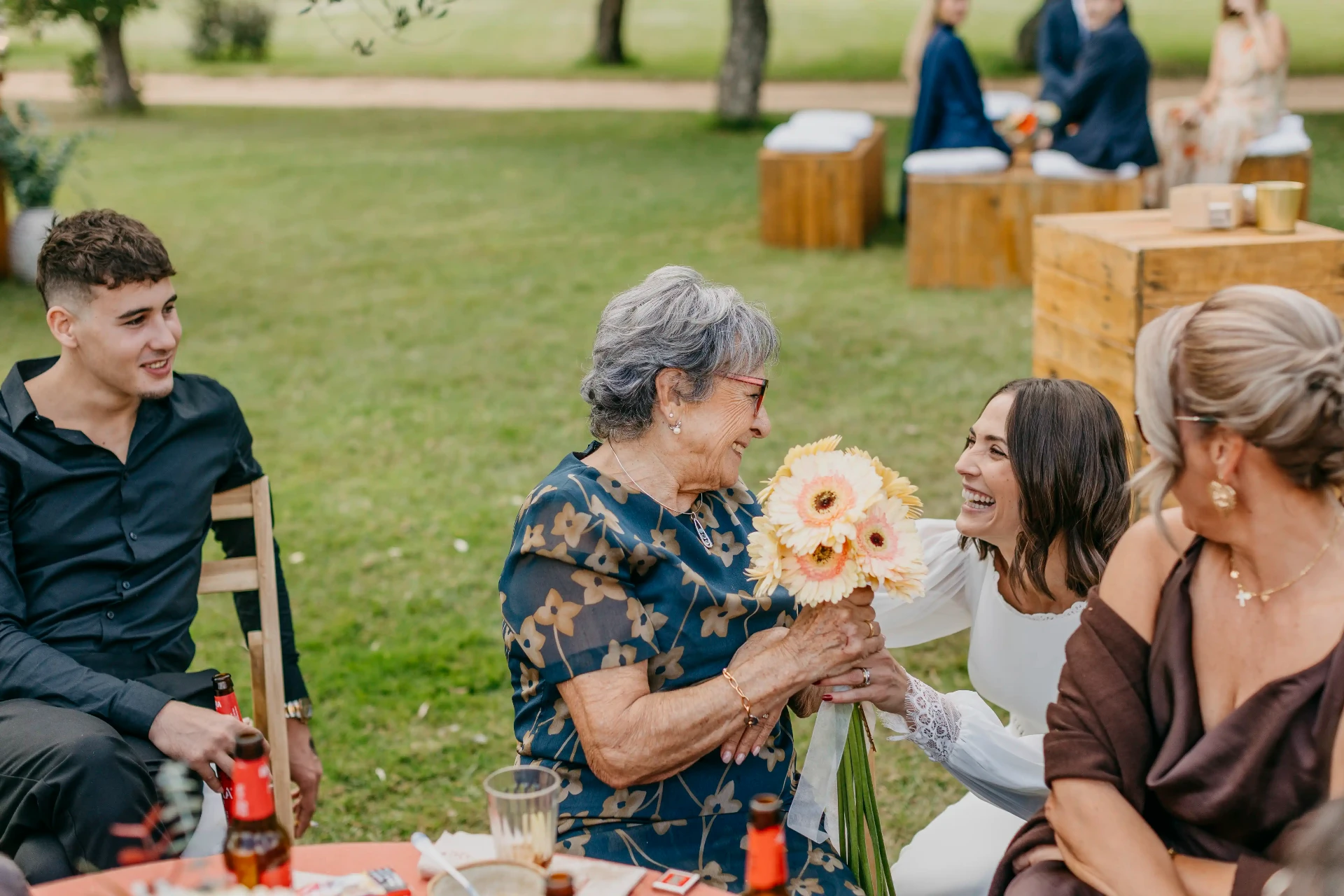 Carla entregando su ramo de gerberas a la abuela durante el aperitivo en el jardín de Can Riera de la Pineda