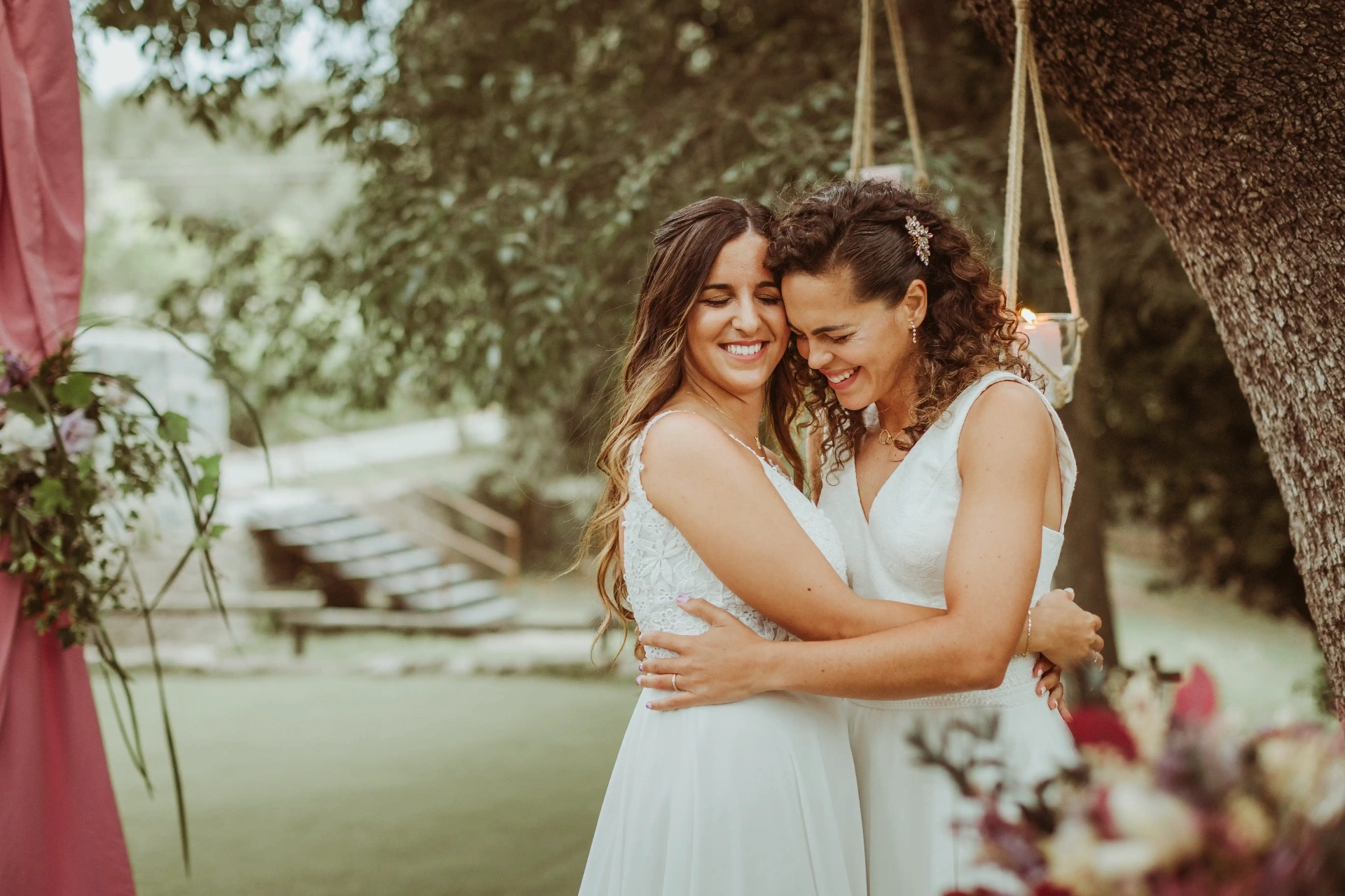 boda LGTBI en El Xaloc, Calders — las novias sonríen abrazadas bajo el árbol del altar tras la ceremonia